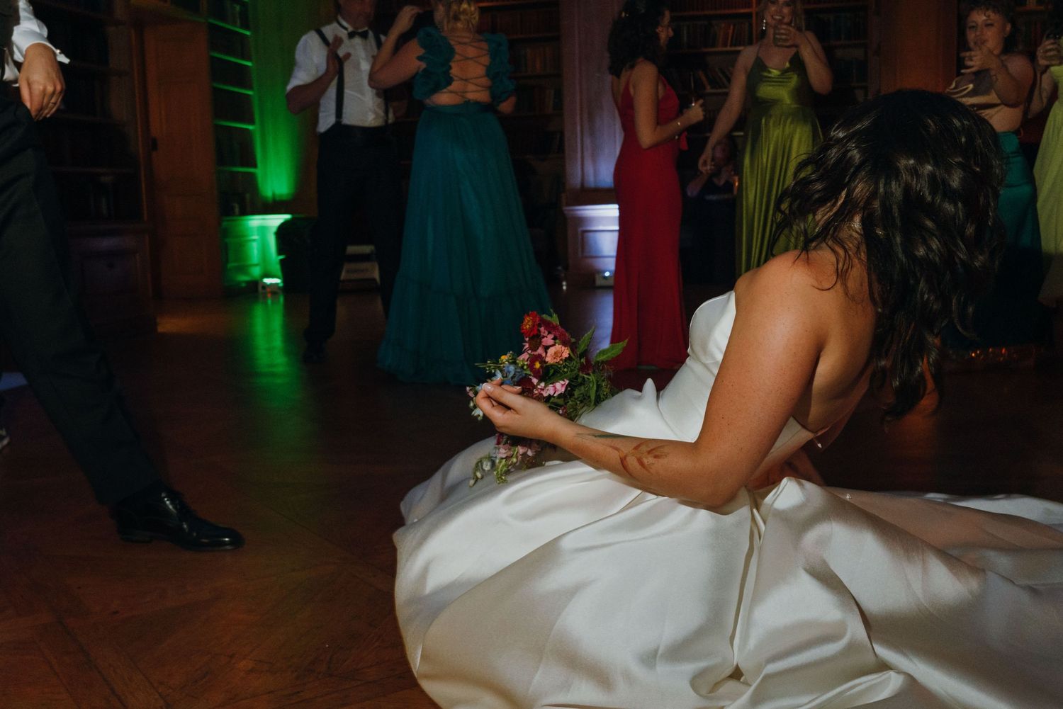 A bride in a white gown sits on the dance floor holding a bouquet at her wedding reception. New Orleans, Louisiana, Mississippi