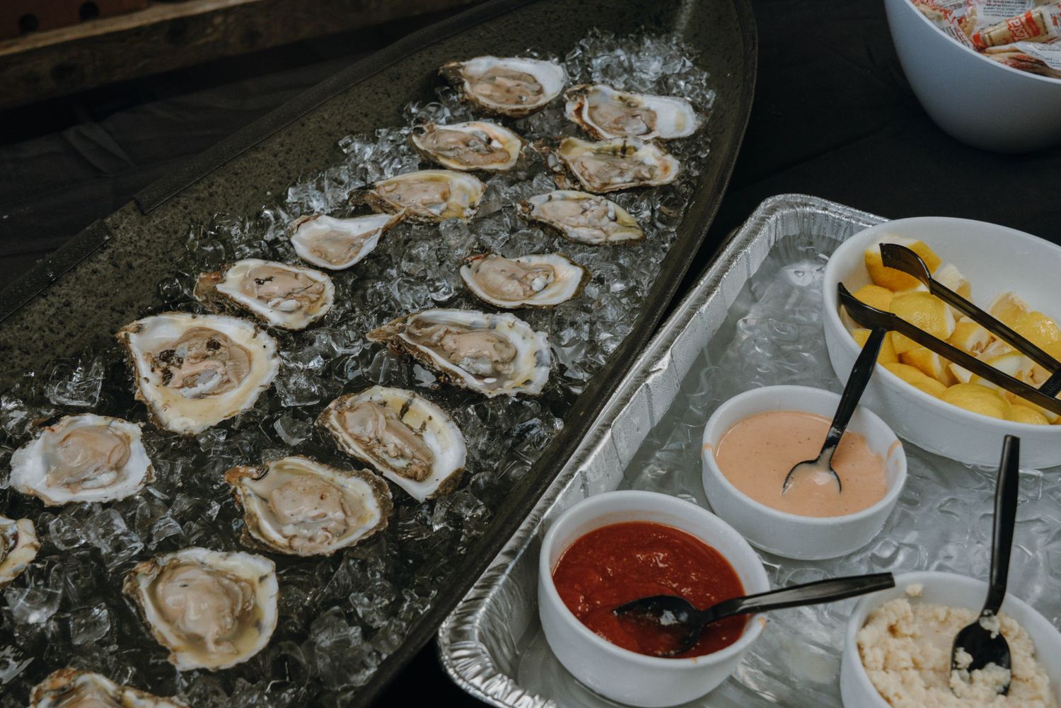 Fresh oysters on ice served with cocktail sauce and condiments at a wedding reception.