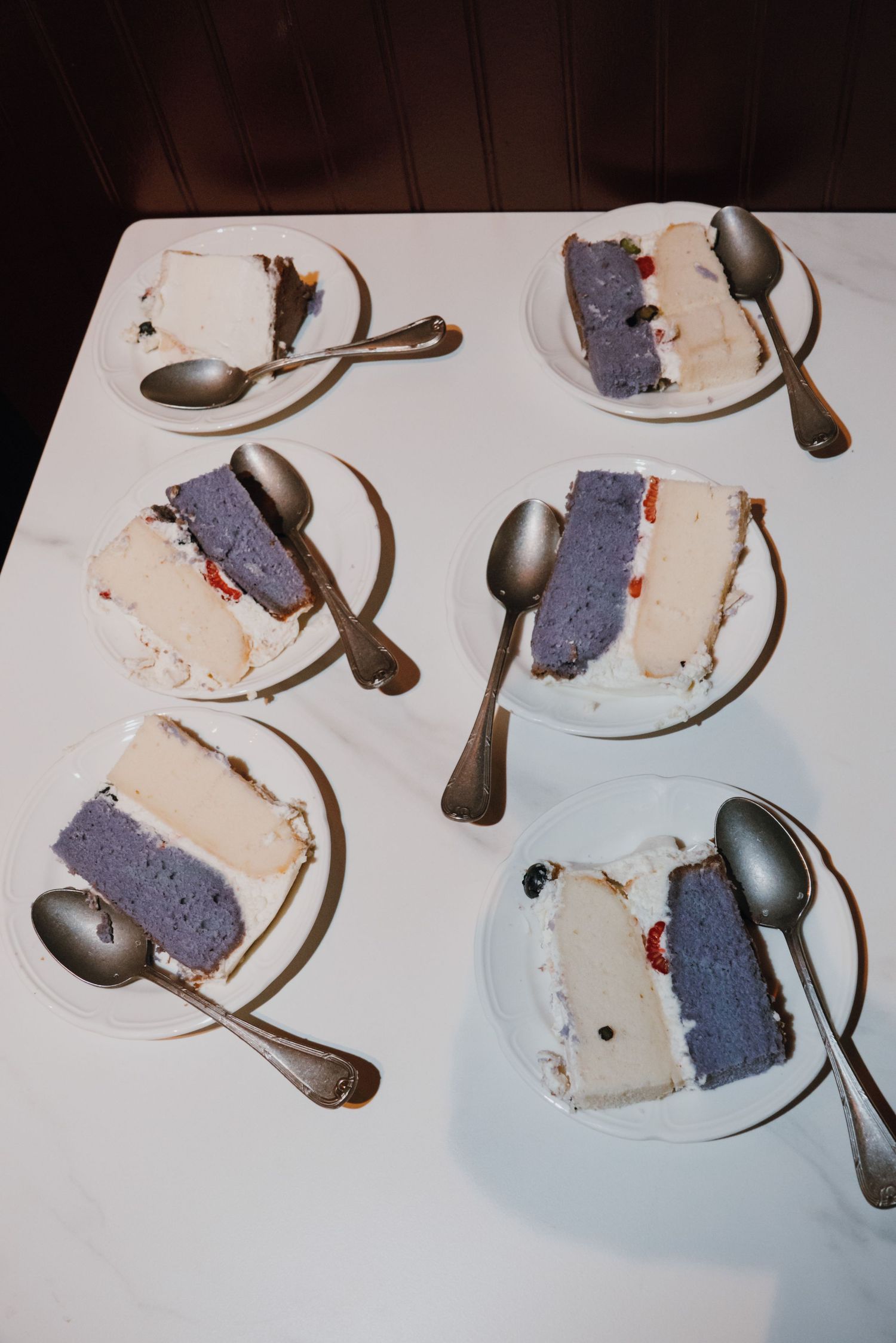 Five plates of two-toned purple and white cake slices with silver spoons on a white tablecloth. New Orleans, Louisiana, Mississippi