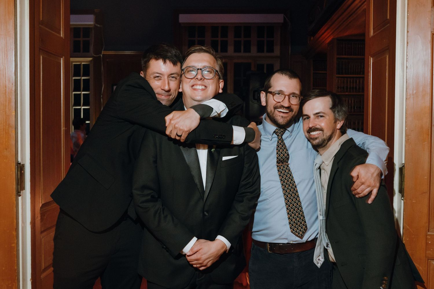 Four men in formal suits smiling and posing together at a wedding celebration. New Orleans, Louisiana, Mississippi