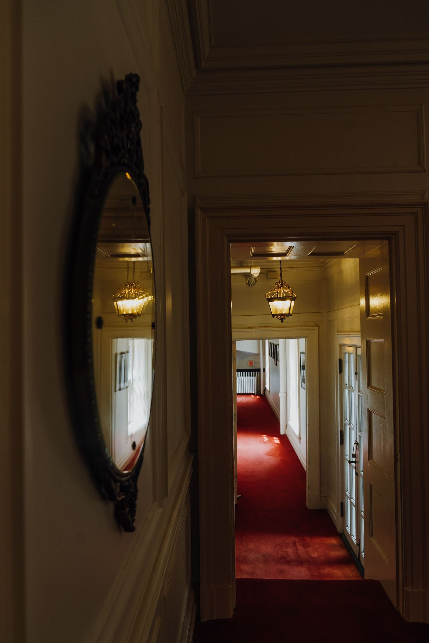 Ornate oval mirror reflecting a hallway with red carpet and gold chandeliers in a historic venue. New Orleans, Louisiana, Mississippi