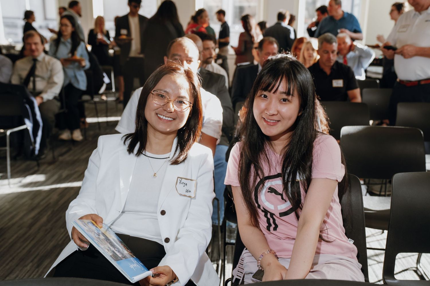 Two smiling young women sitting together at a Tulane Innovation Institute conference event.