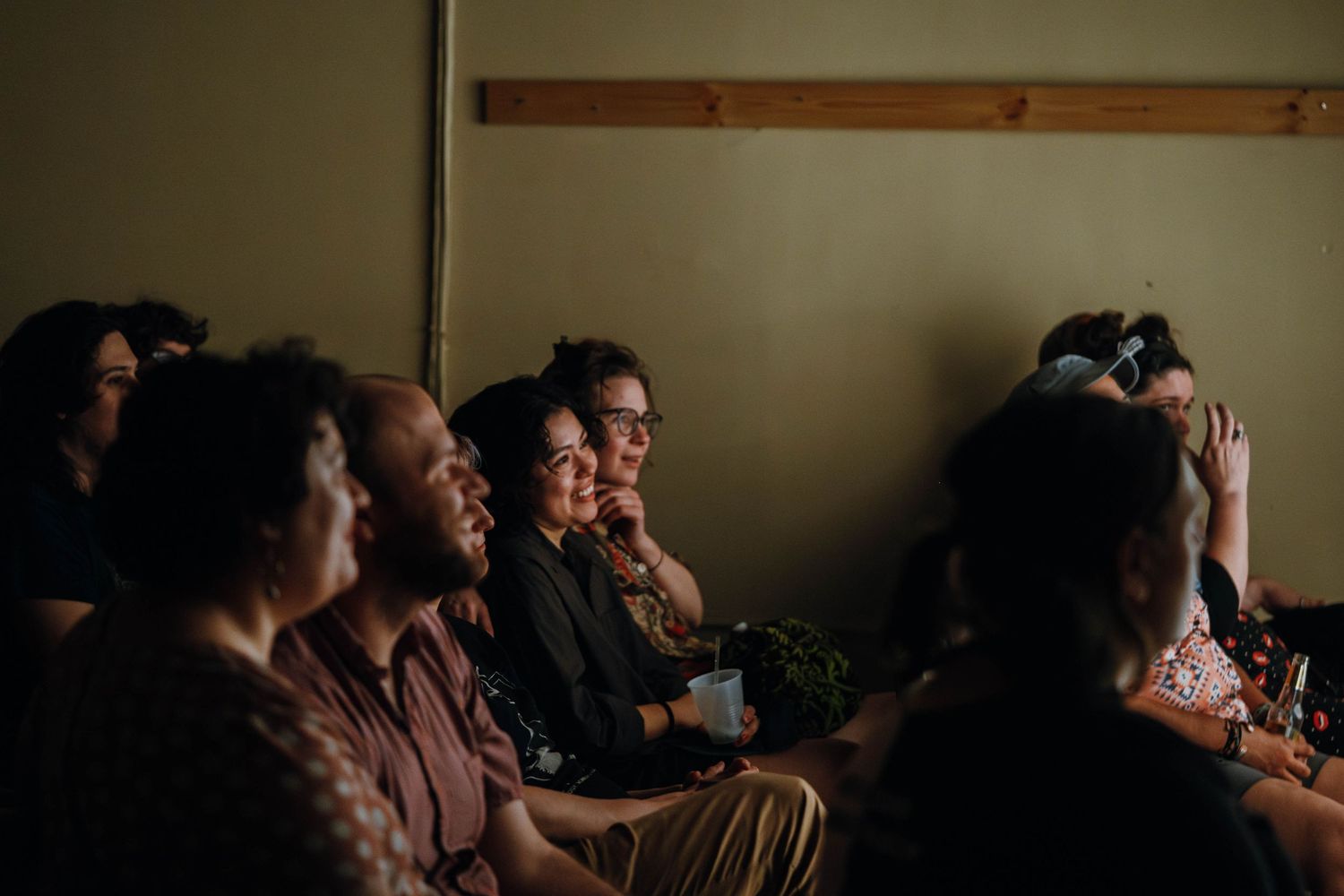 Engaged audience smiles and photographs during intimate indoor performance event.