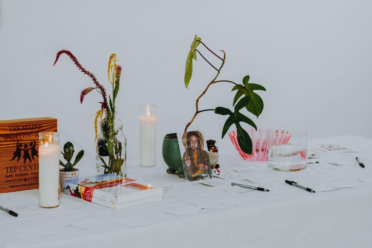 A styled table display features candles, plants, books, and decorative objects against a white background.