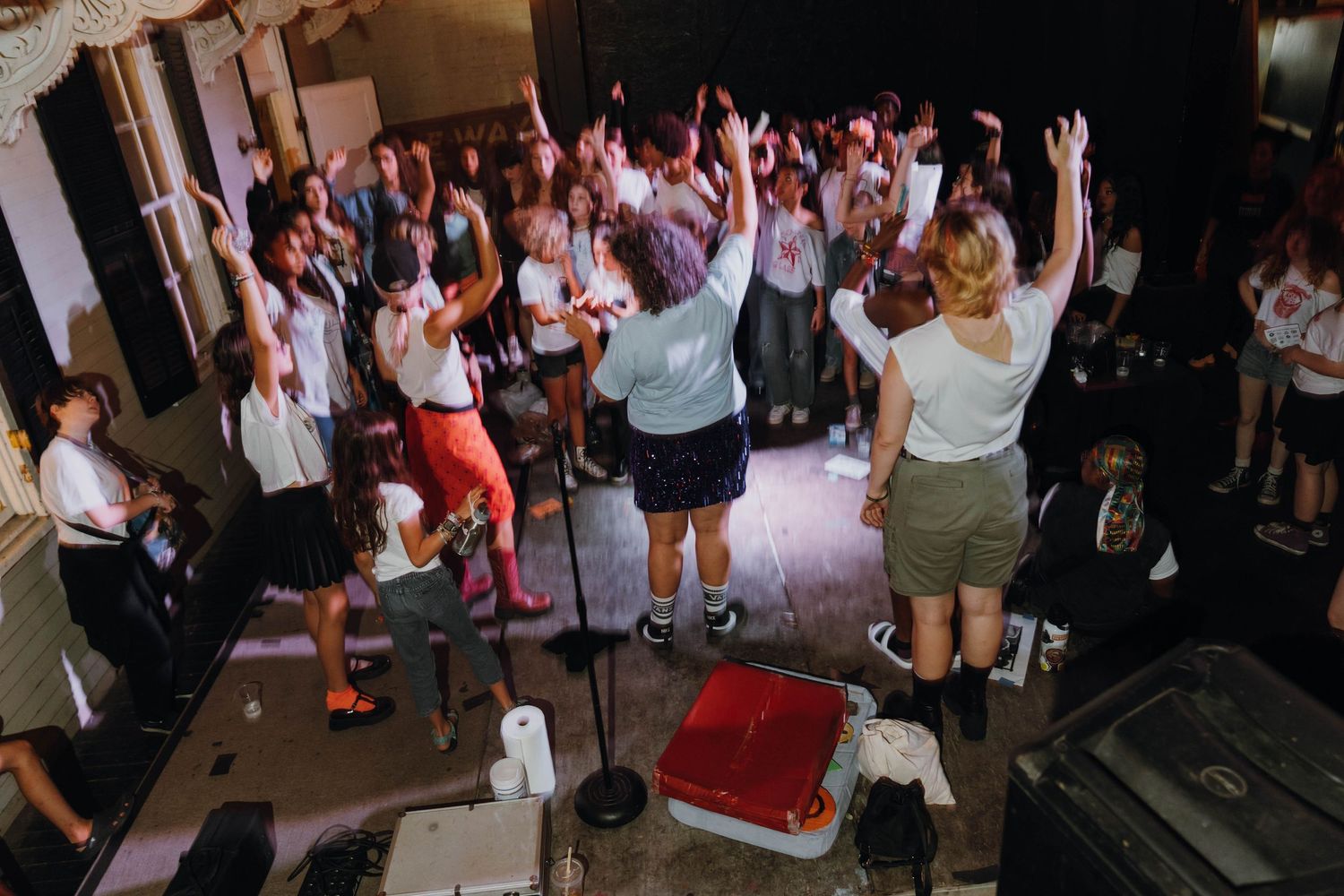 Energetic crowd with hands raised at an indoor music concert with performers on stage. New Orleans, Louisiana, Mississippi