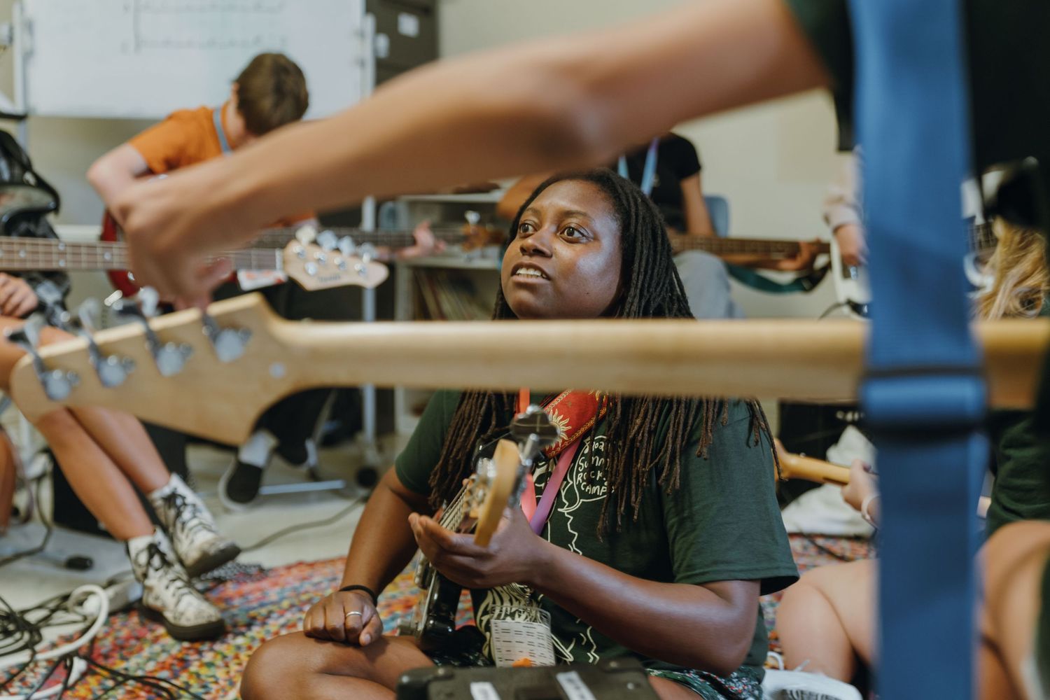 Young girl with braids sits cross-legged on floor holding an instrument during a music class session. New Orleans, Louisiana, Mississippi