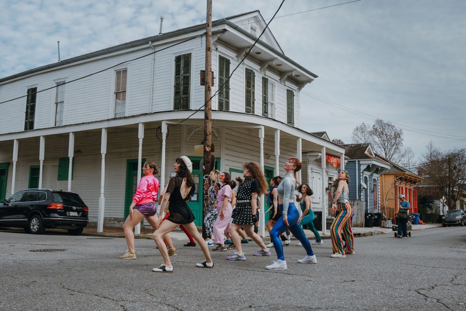 Group of dancers in festive attire performing outdoors on a New Orleans street corner.
