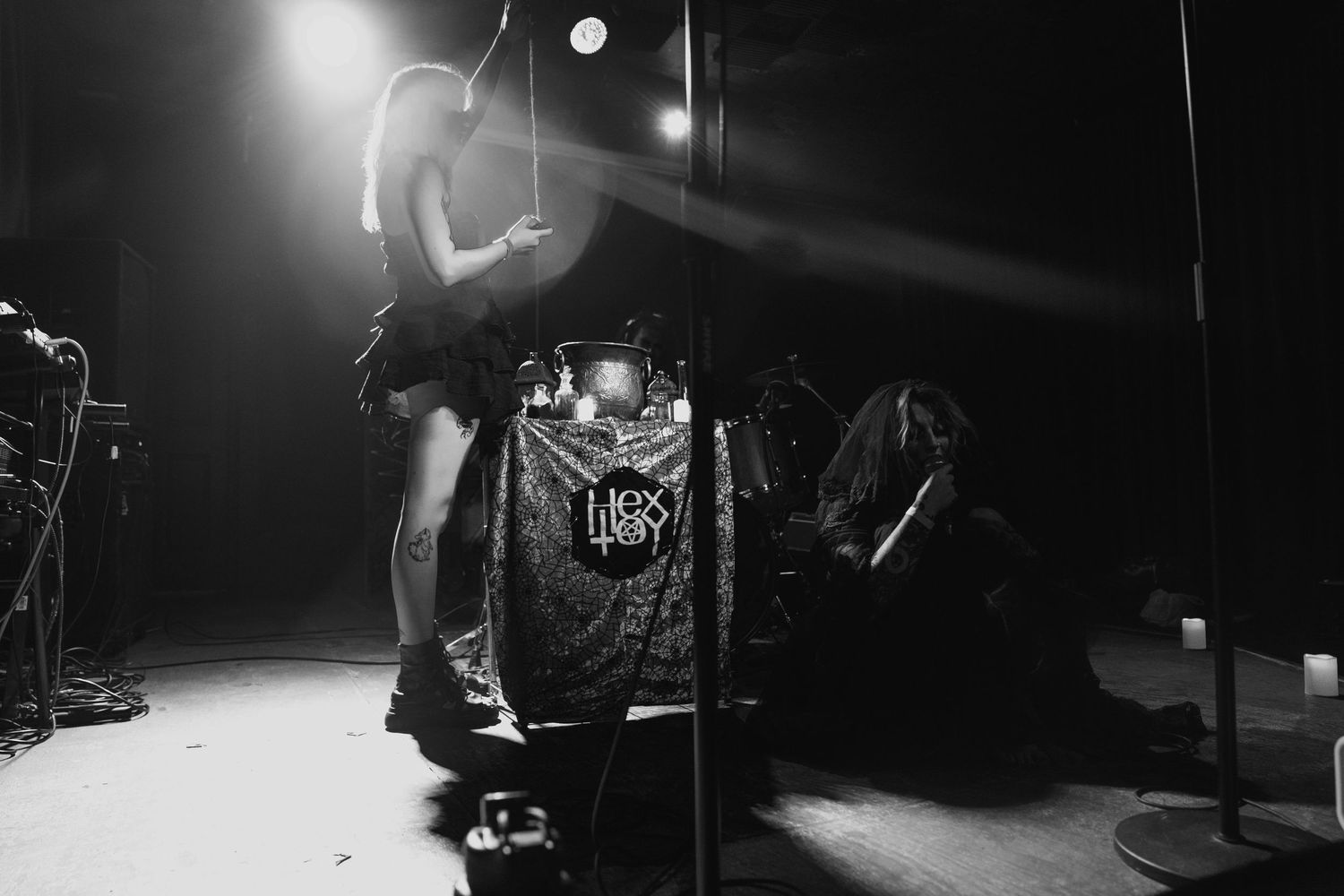 Black and white concert photo of performer on stage with band logo banner under spotlight.