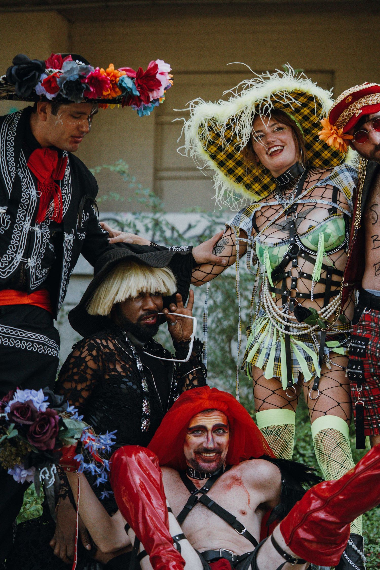 Group of five people in eclectic colorful costumes posing and laughing together at an outdoor event.