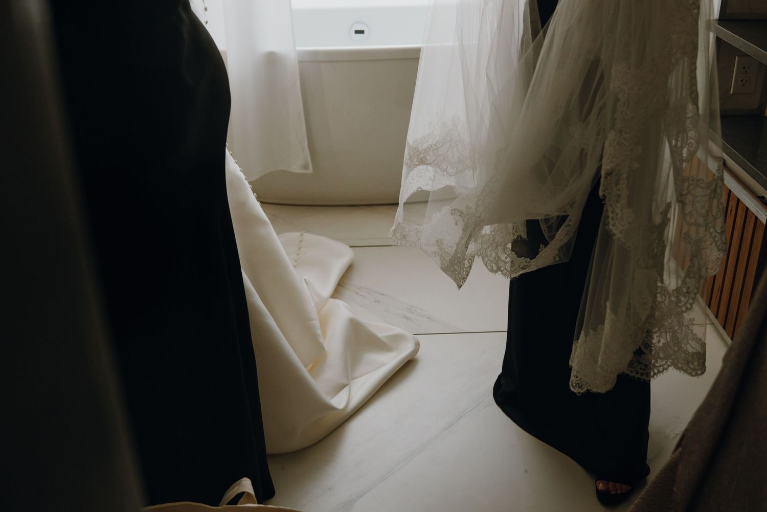 Close-up of a wedding dress and veil hanging in a bright room before the ceremony.