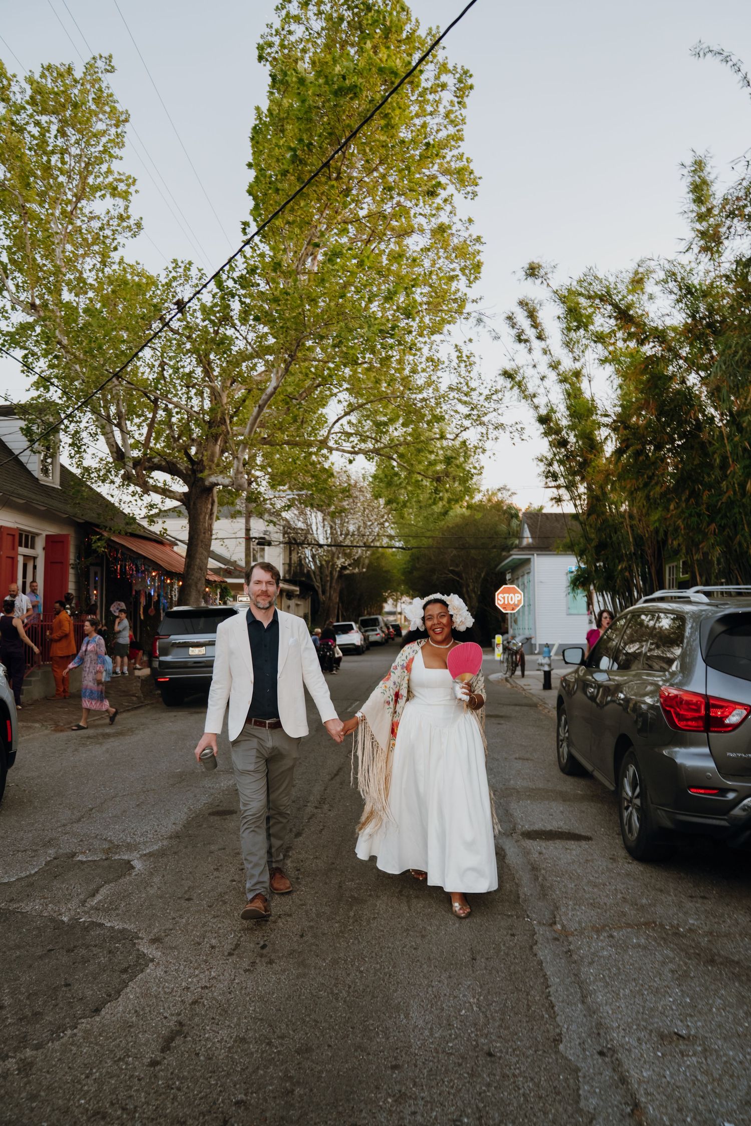 Bride and groom walk hand-in-hand down a street at golden hour after their wedding.