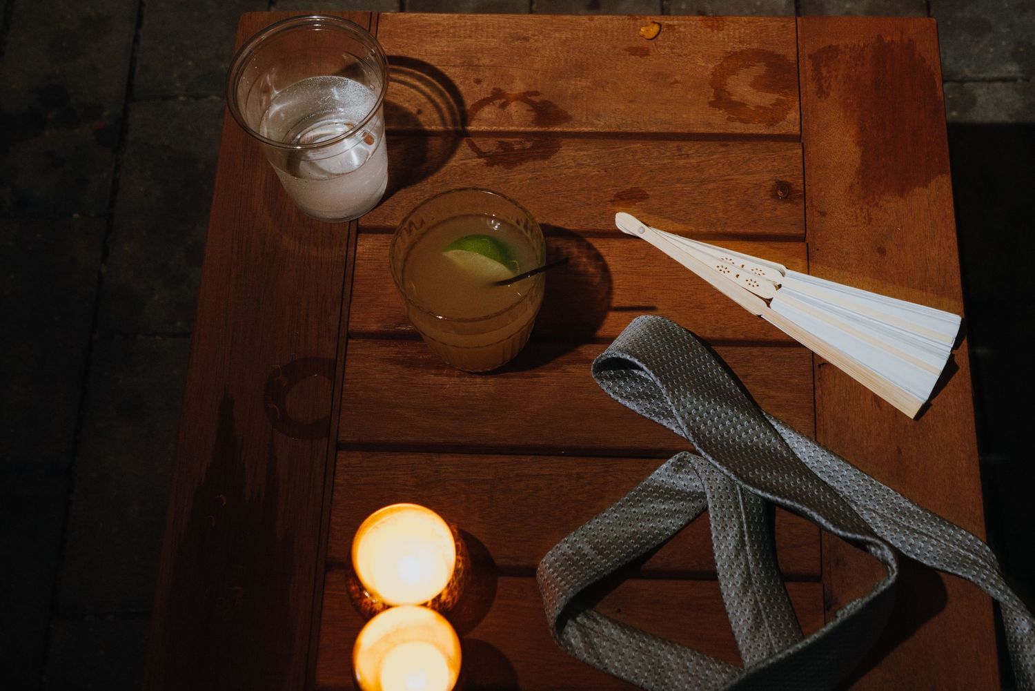 Rustic wooden table with cocktails, candles, white paper fan, and plaid ribbon at evening wedding reception. New Orleans, Louisiana, Mississ