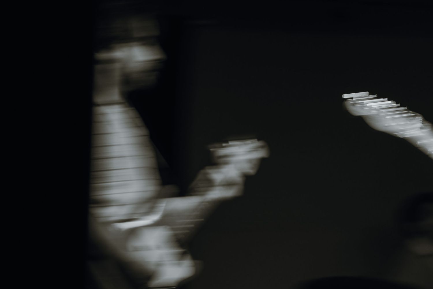 Abstract blurred black and white image of a musician playing guitar on a dark stage.