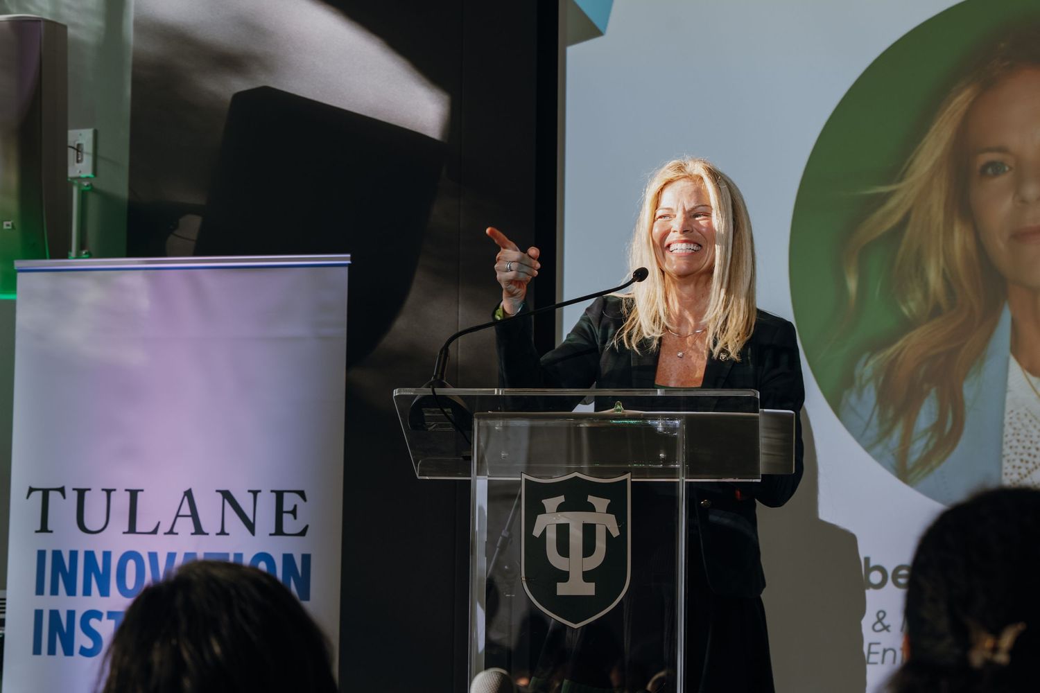 Woman speaking enthusiastically at a Tulane Innovation Institute podium during a formal event.