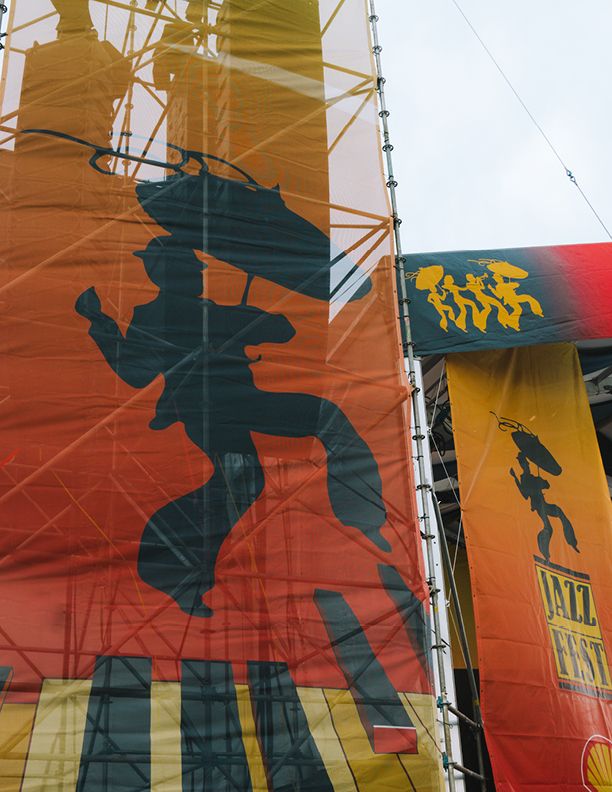 Colorful jazz festival banners featuring silhouette of a musician with umbrella on orange and yellow background.