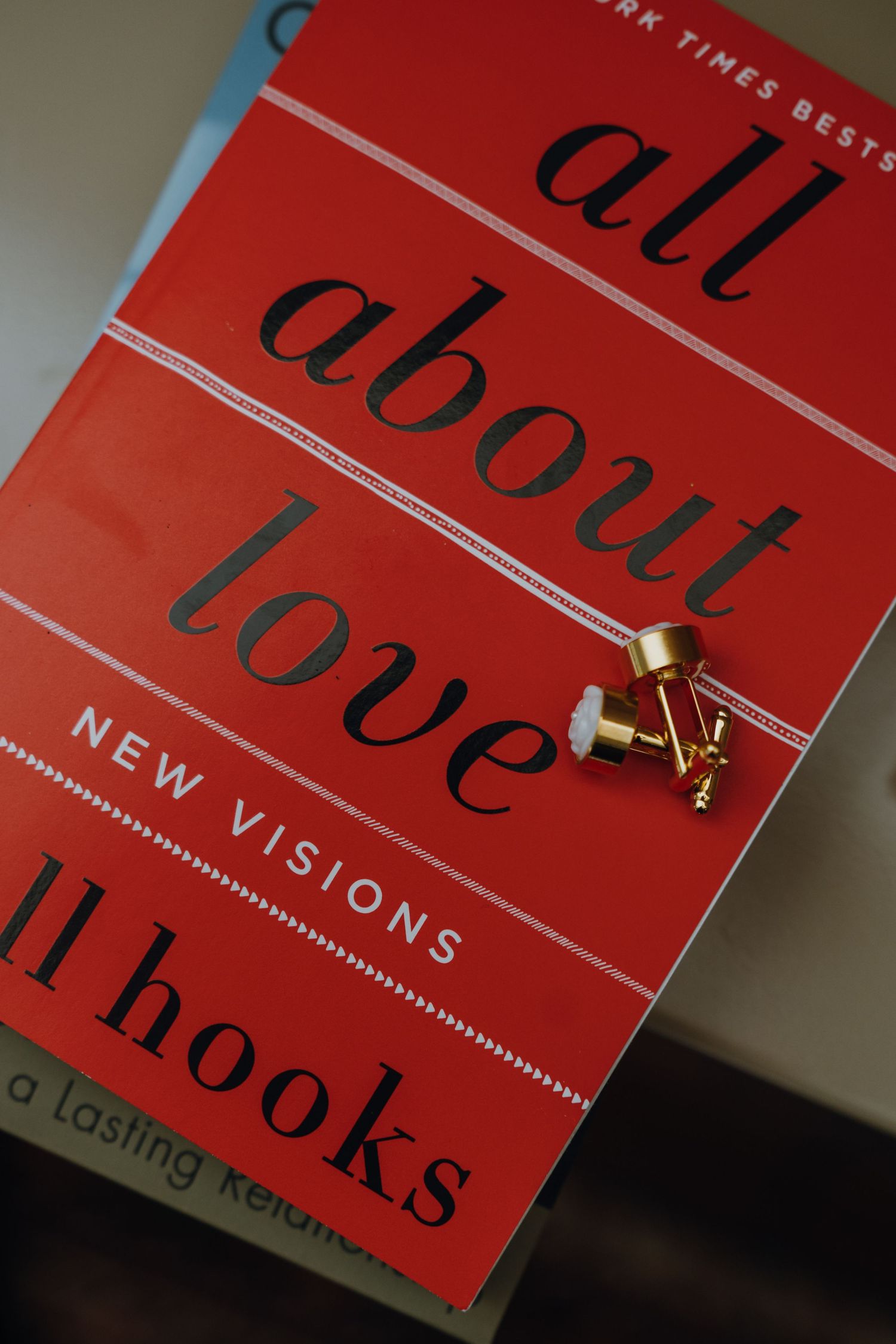 Gold cufflinks resting on red cover of bell hooks All About Love New Visions book. New Orleans, Louisiana, Mississippi