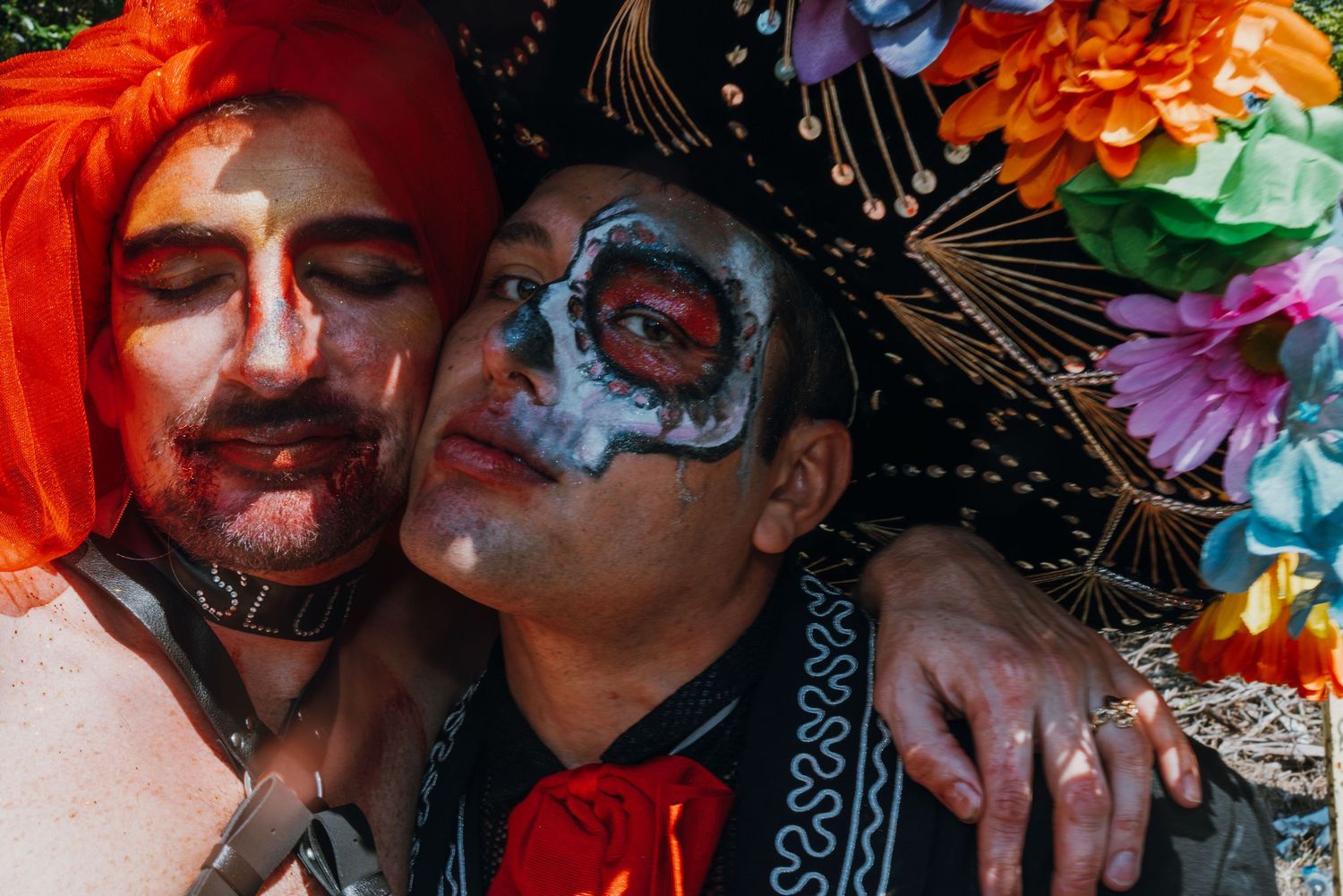 Two people in Day of the Dead makeup and costumes posing closely together.
