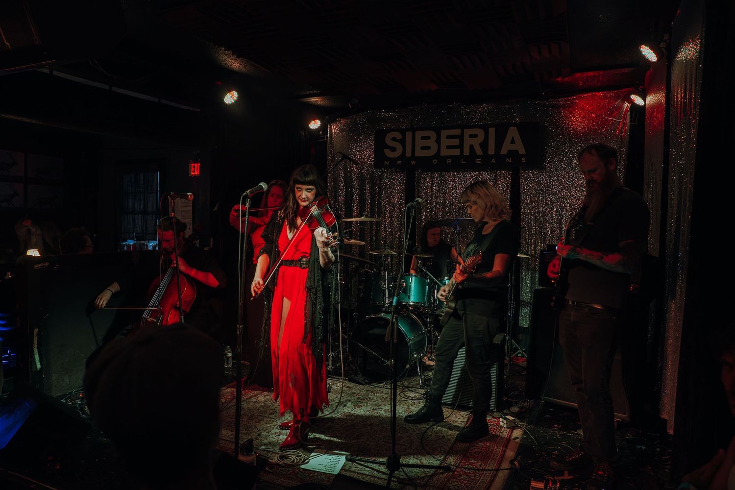 Singer in flowing red dress performs with band on stage at Siberia music venue.