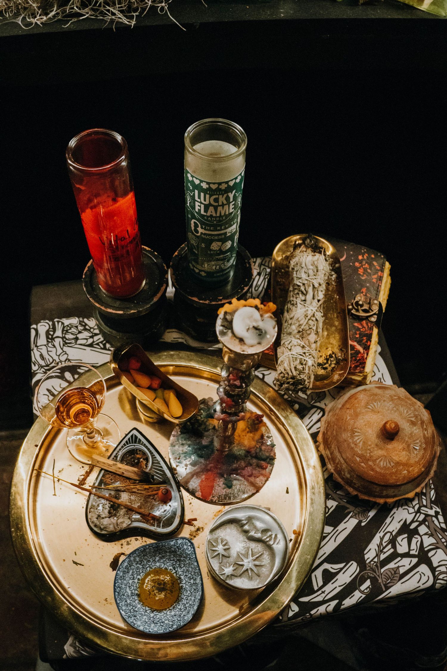 A mystical altar tray with candles, crystals, and ritual objects arranged on a decorative cloth.