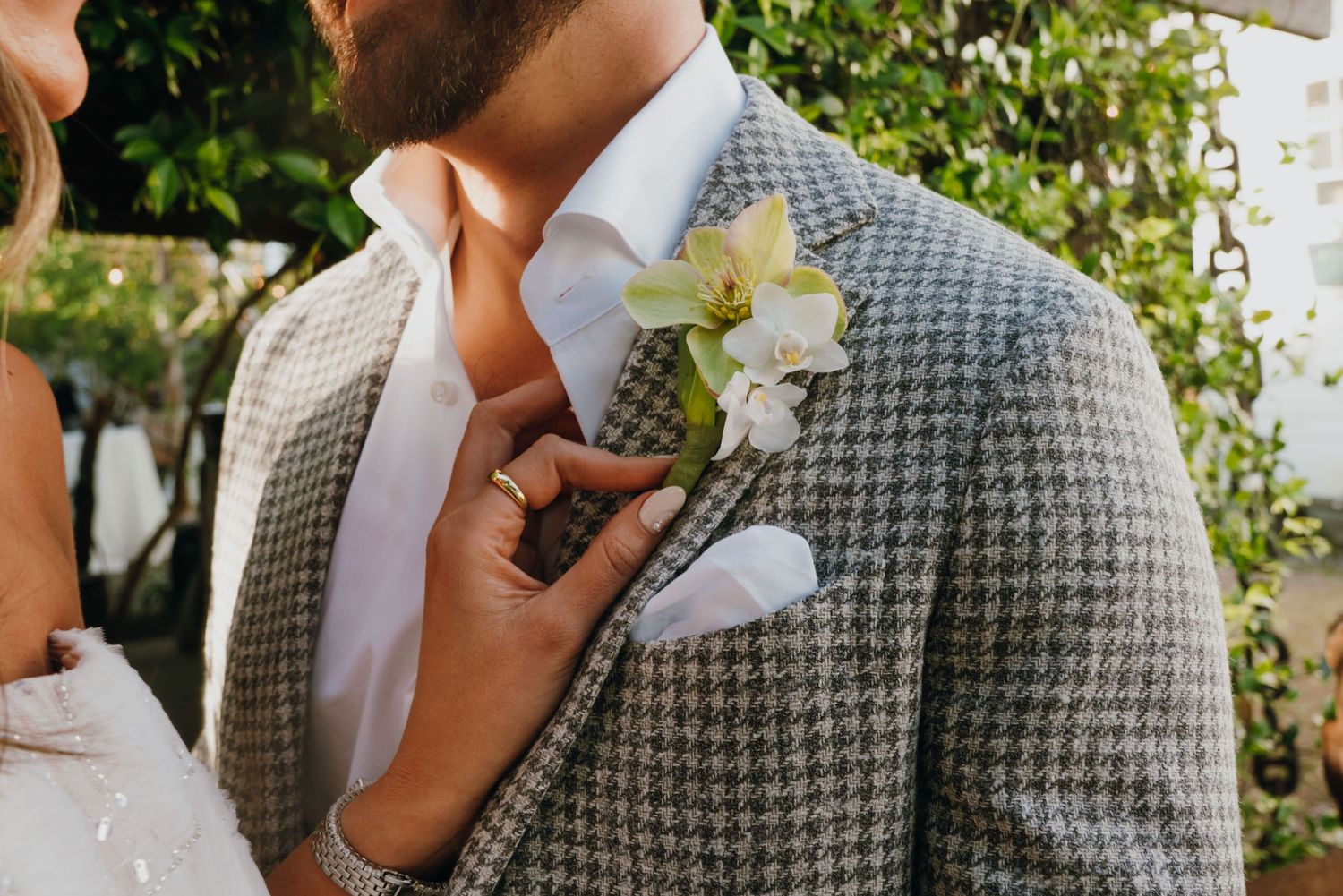 Close-up of groom's grey houndstooth suit lapel with white orchid boutonniere and white pocket square.