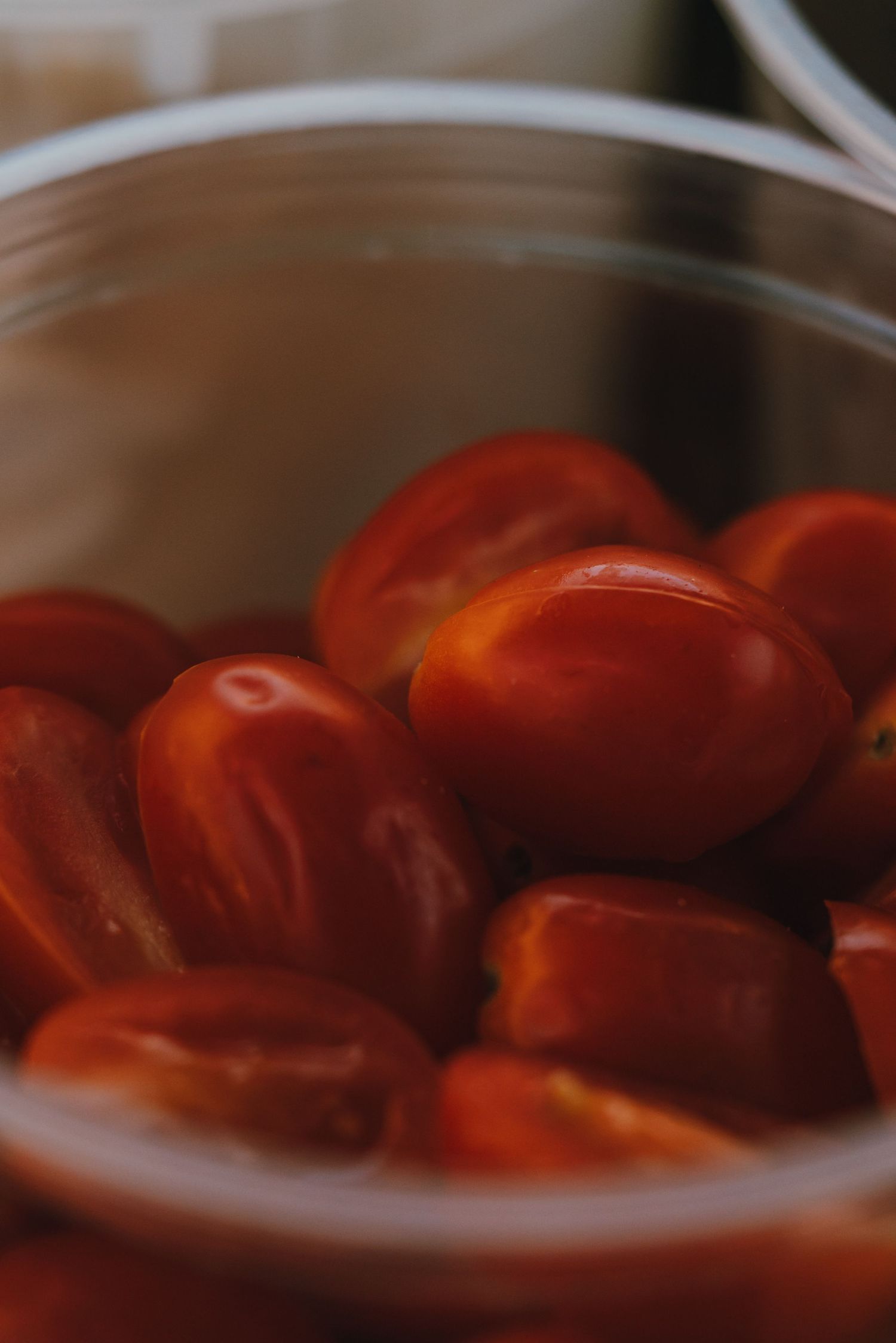 Fresh red cherry tomatoes in a clear glass bowl, close-up food photography.