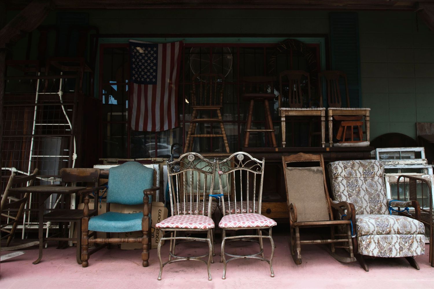 Vintage antique chairs and furniture displayed outside a secondhand shop with American flag.