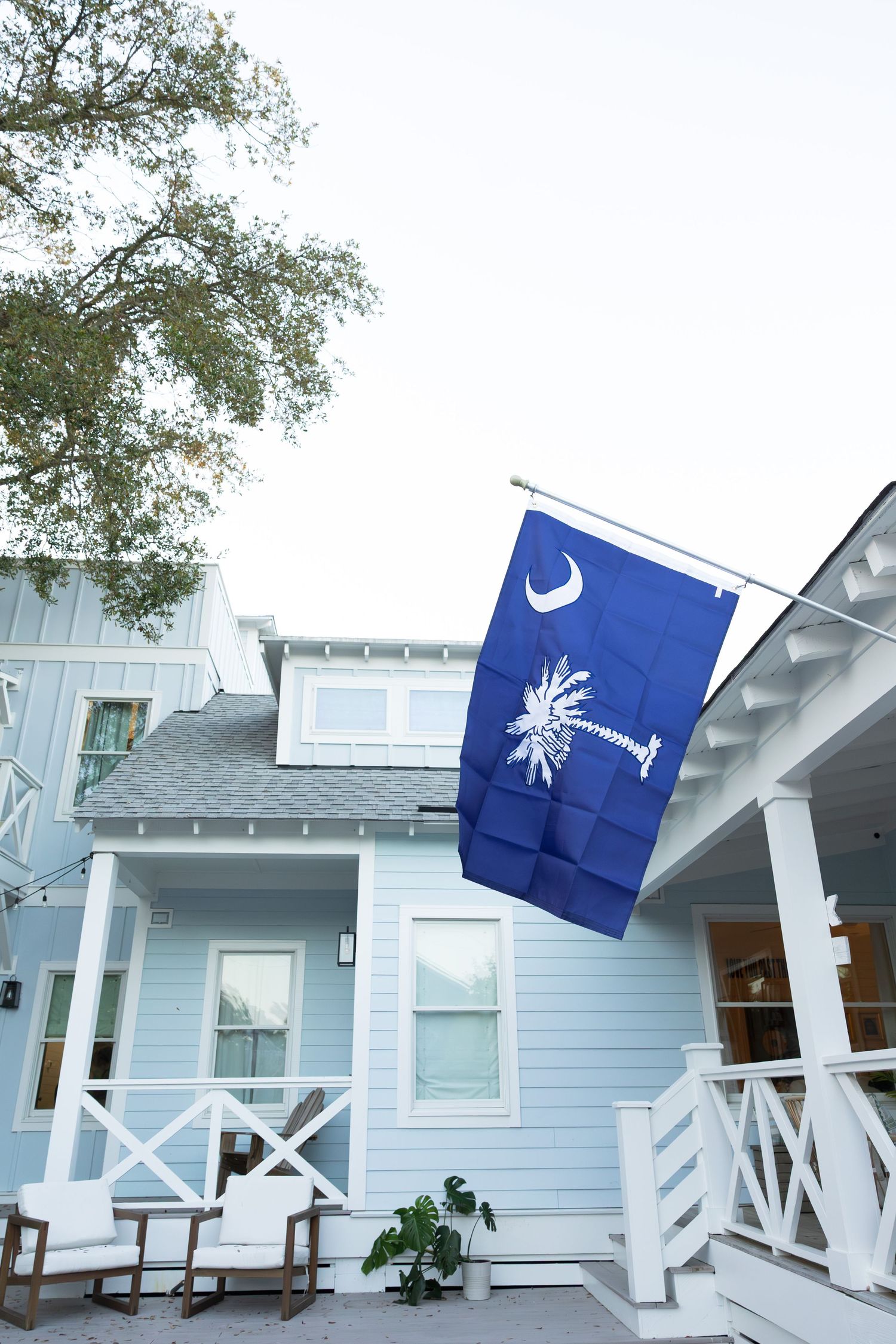 A row of light blue beach houses with white trim and South Carolina state flags flying in the breeze.