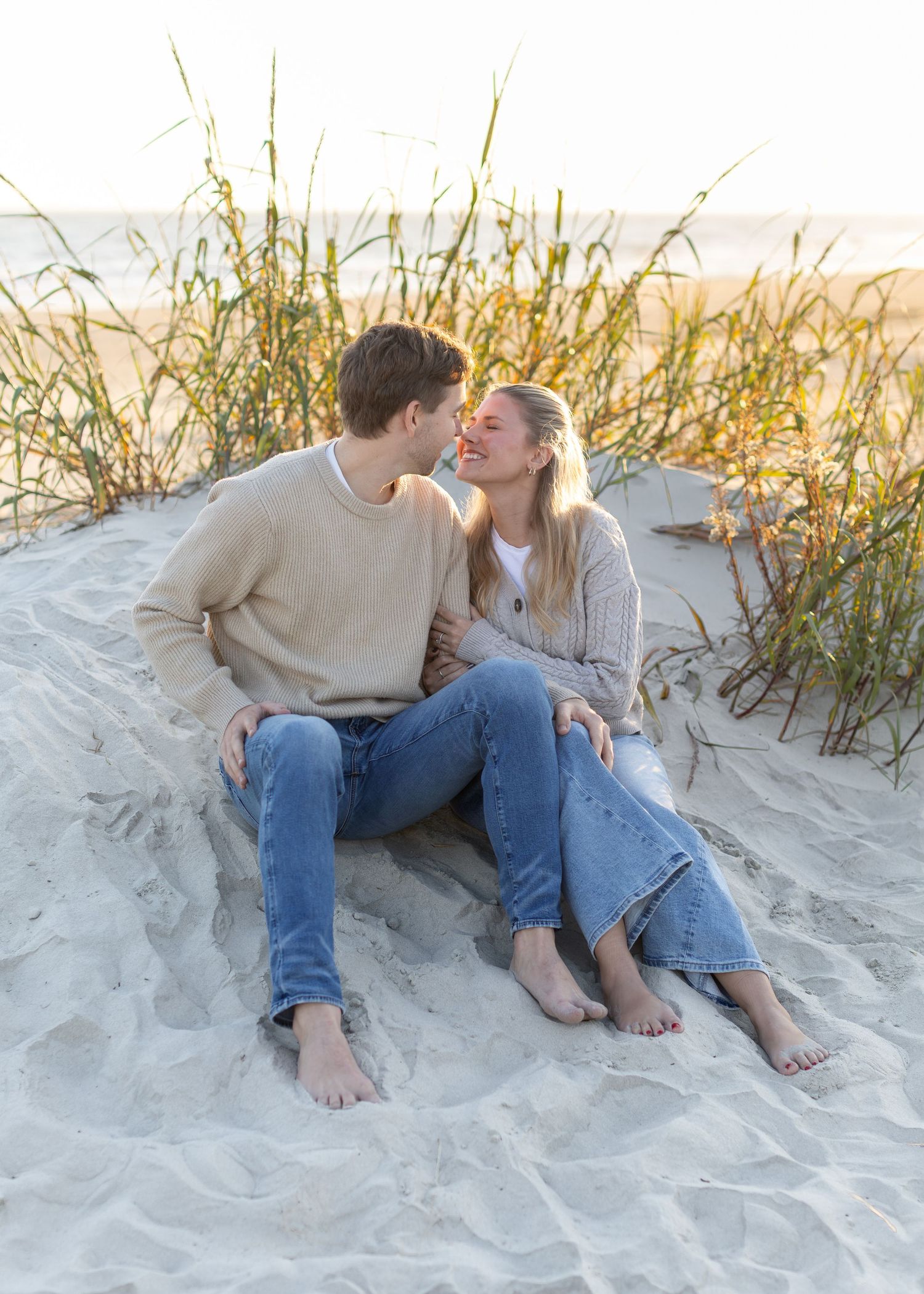 Couple sharing romantic moments on Sullivan's Island sand dunes during golden hour.
