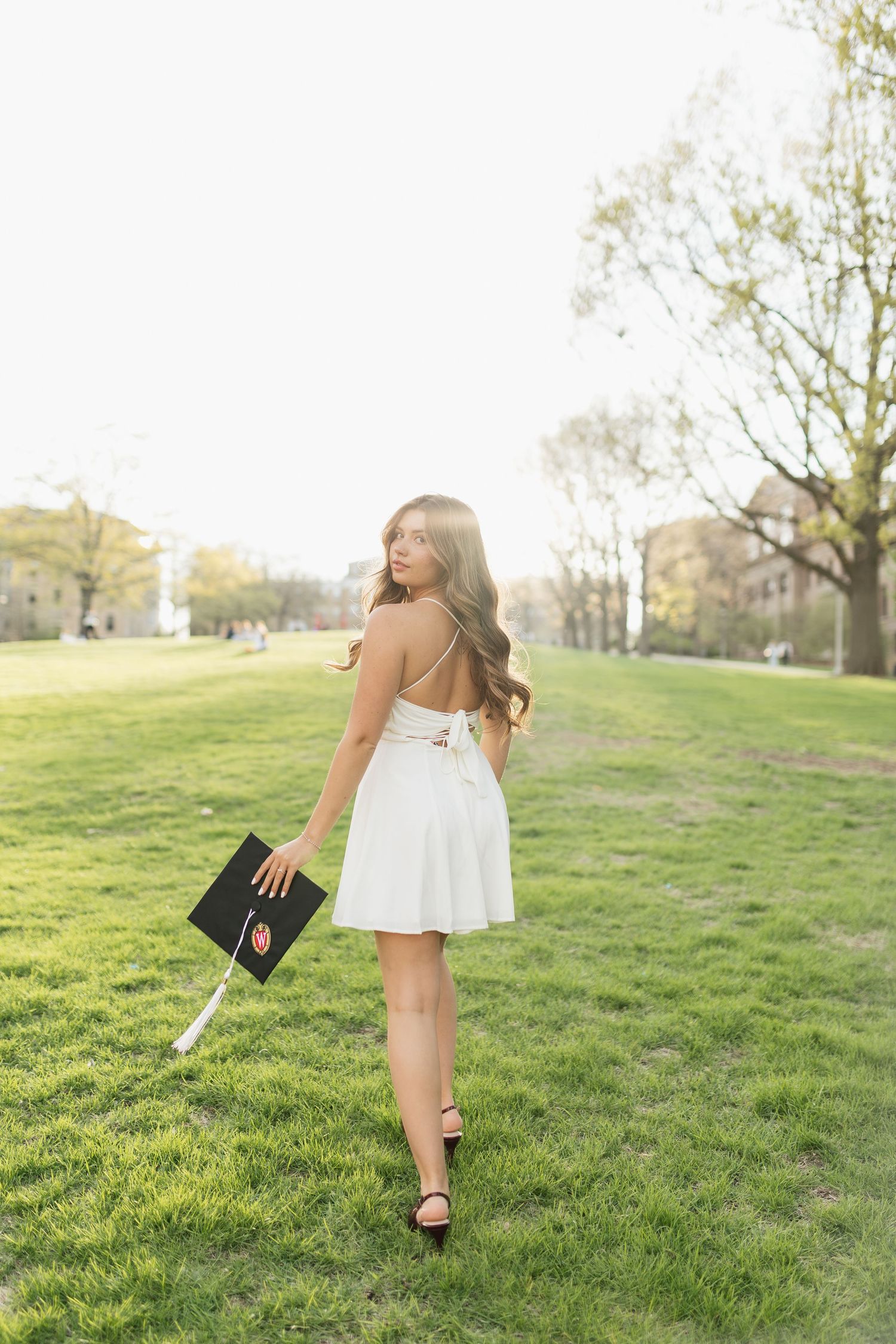 UW Madison graduate in a white dress dances and twirls gracefully on Bascom Hill at UW Madison.