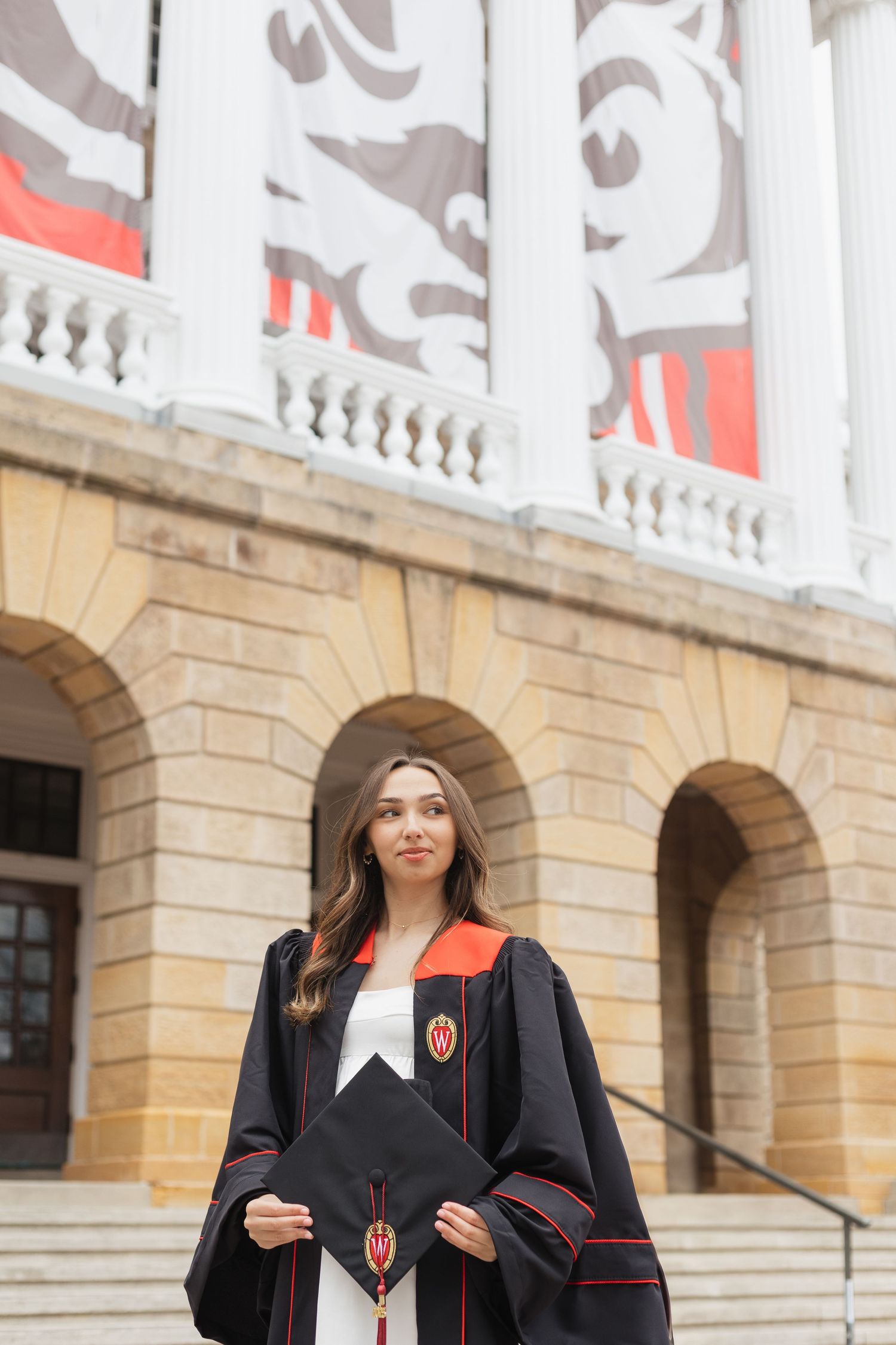 Graduate celebrating in front of classical university architecture with white columns.