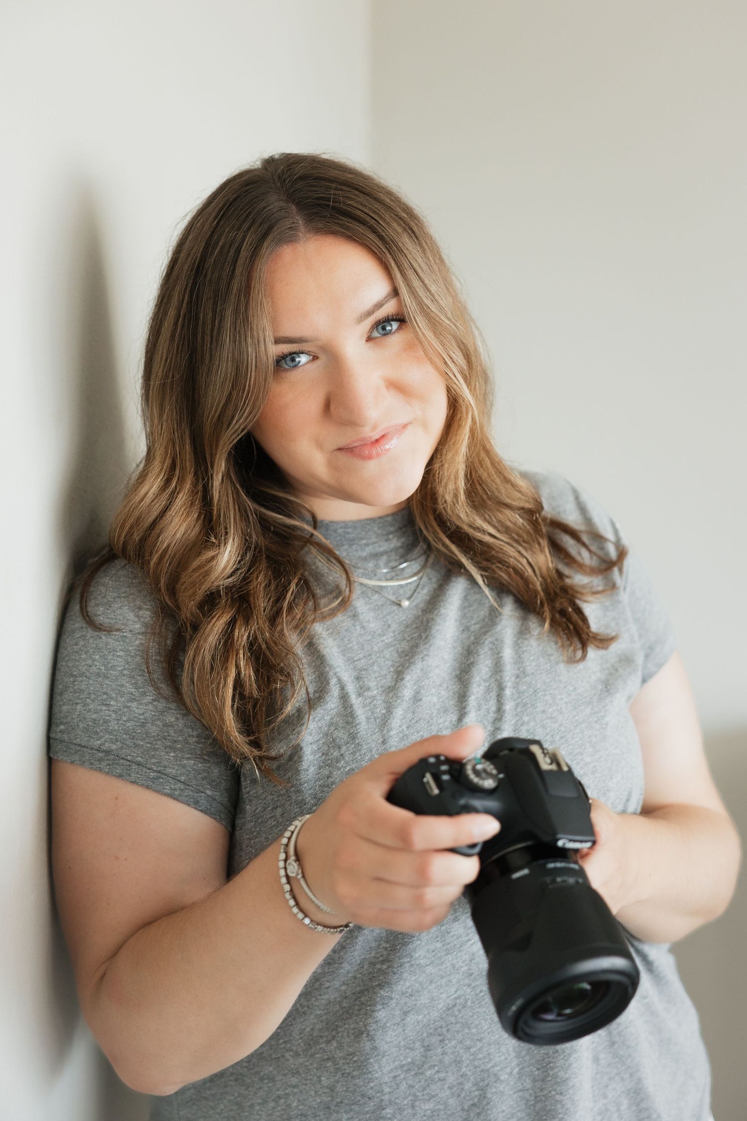 A owner and photographer in a gray t-shirt holding a camera with playful expressions.