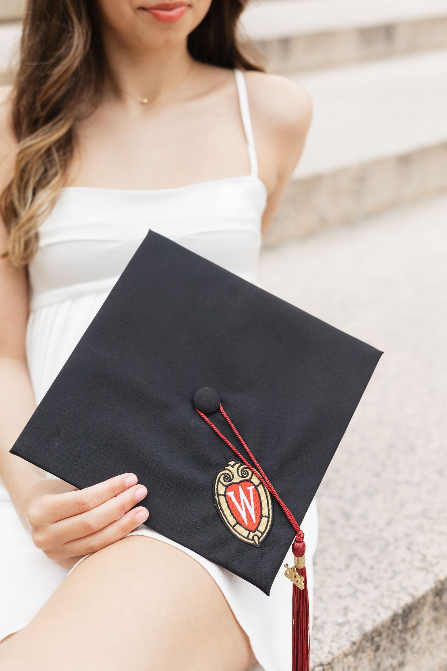Close-up of graduation cap with University of Wisconsin Madison emblem and tassel.