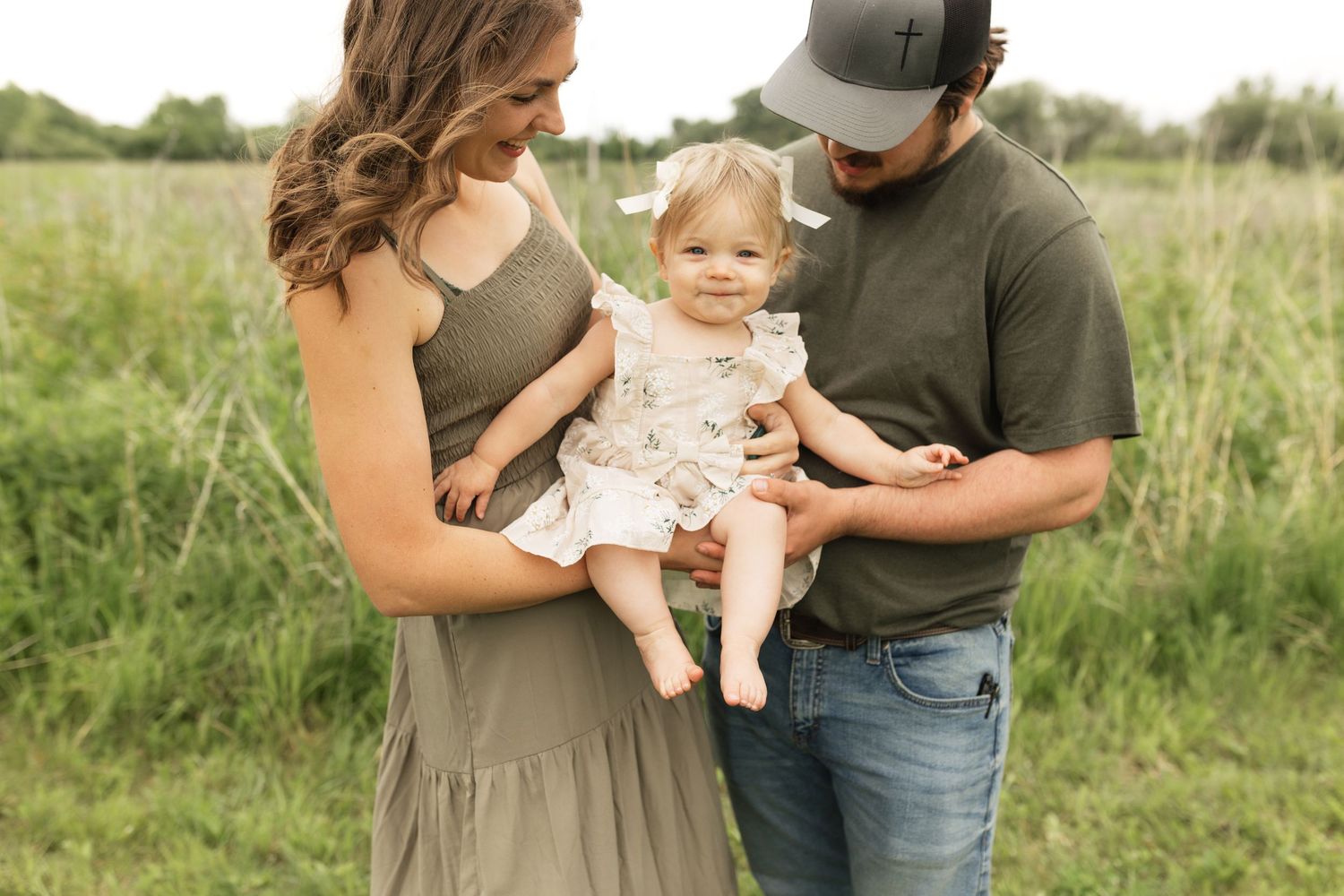 A family shares tender moments together in a sunny outdoor field.