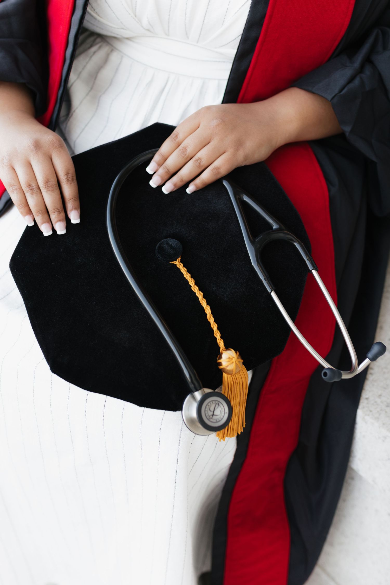 Close-up view of a graduation cap tassel against a black and red academic gown.