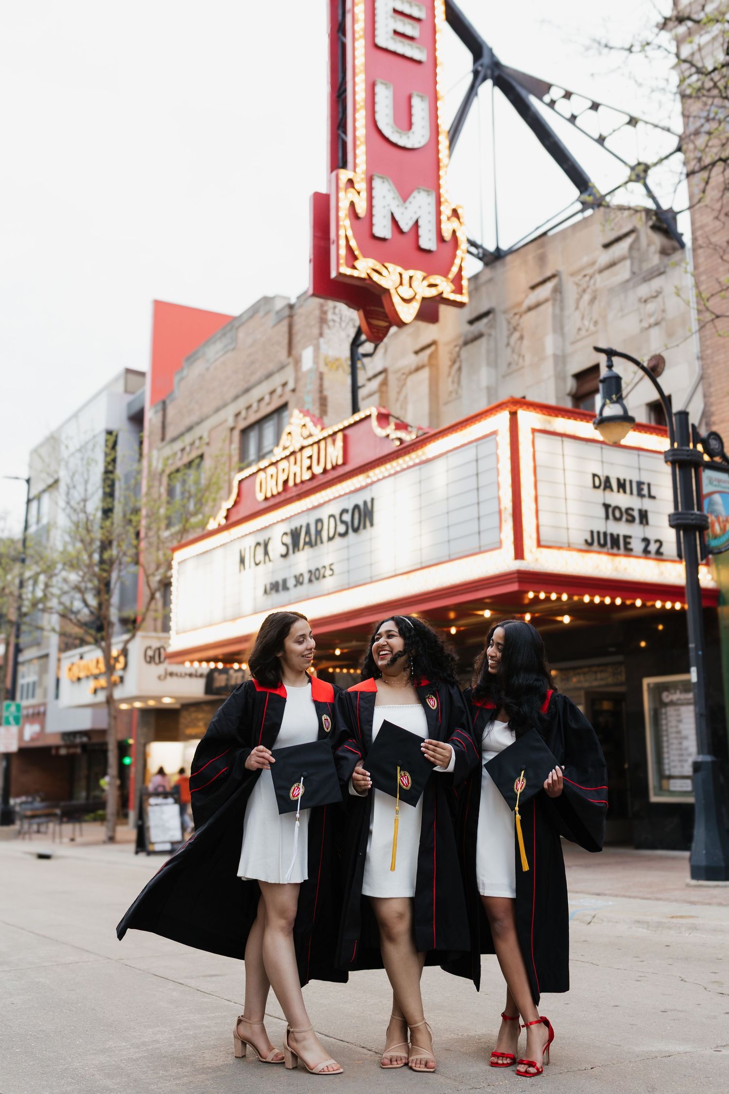 Graduation photo shoot in front of a vintage movie theater with red marquee signs.