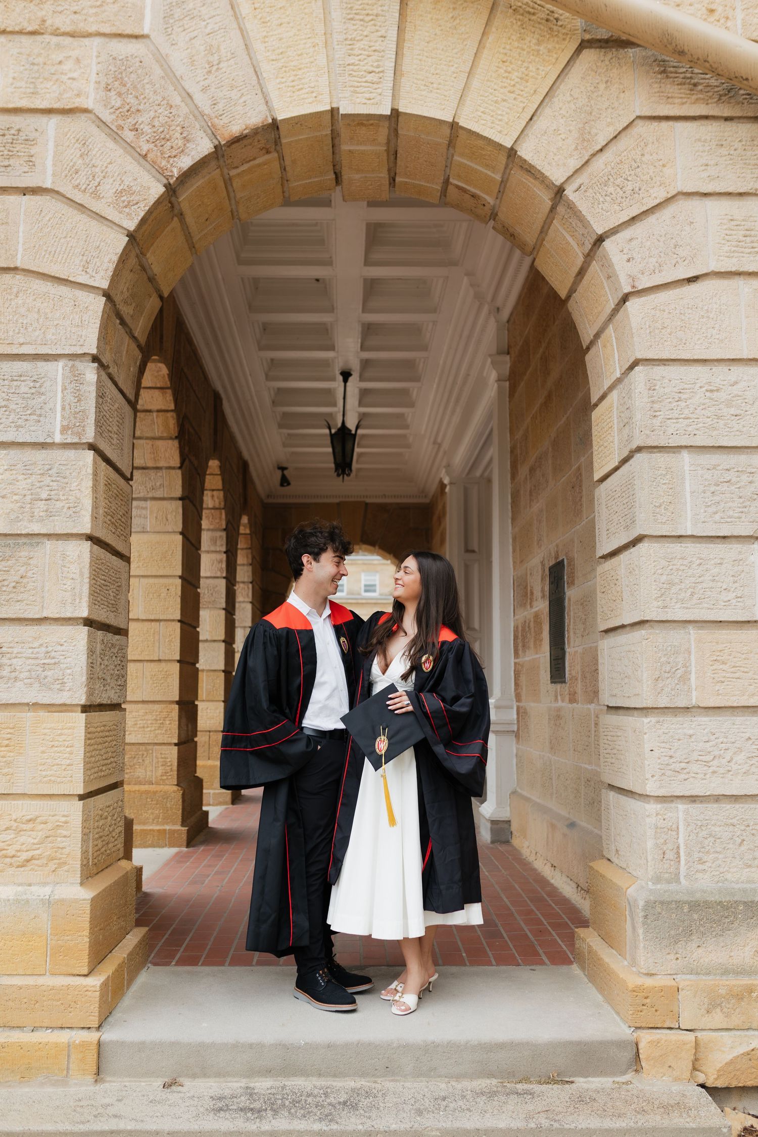 Graduates celebrate under stone archways of historic university building.