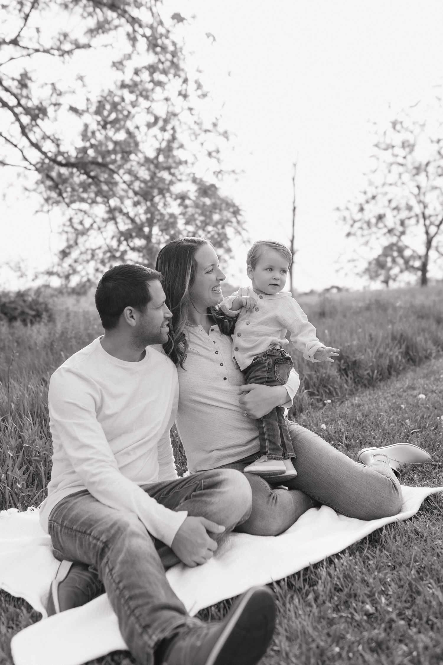 Black and white portrait of a family relaxing together on a blanket outdoors.