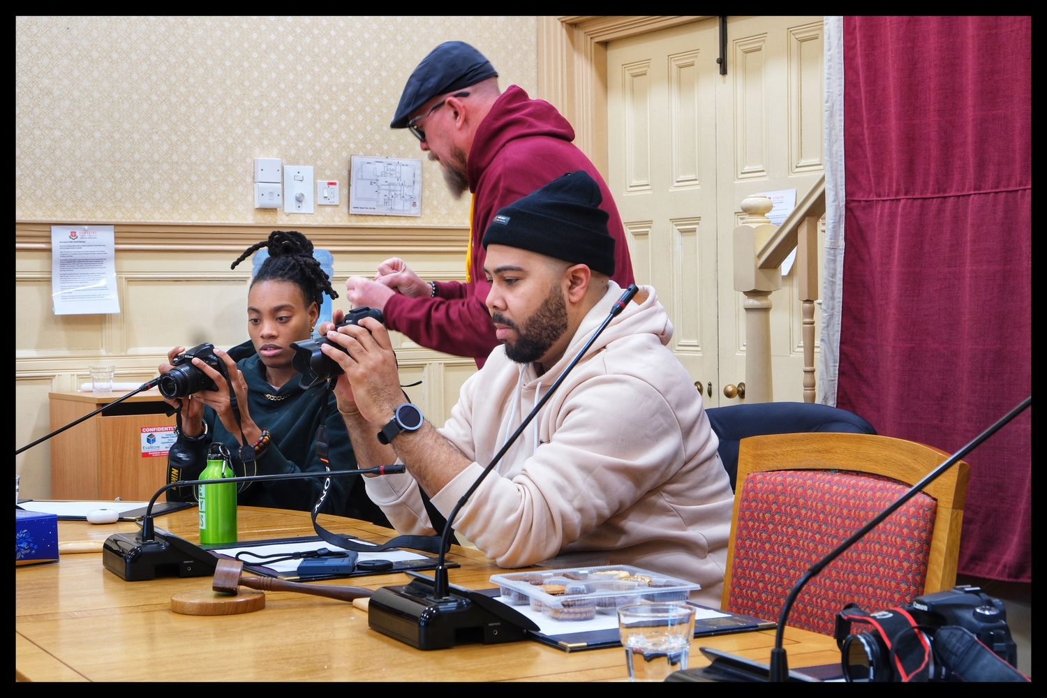 Rob Kirman with two students working at a conference table in an ornate meeting room.