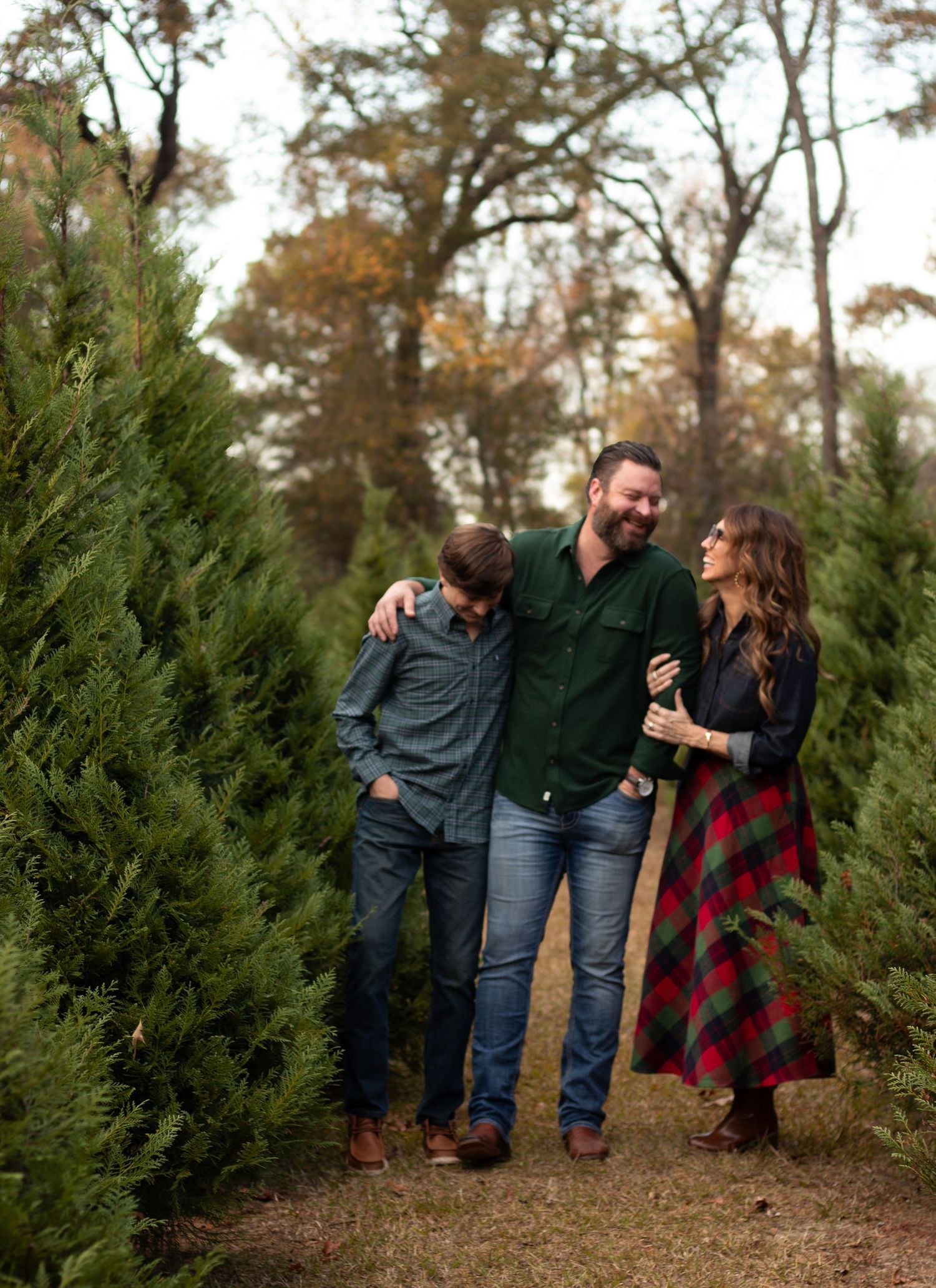 Family walking together through a Christmas tree farm at sunset.