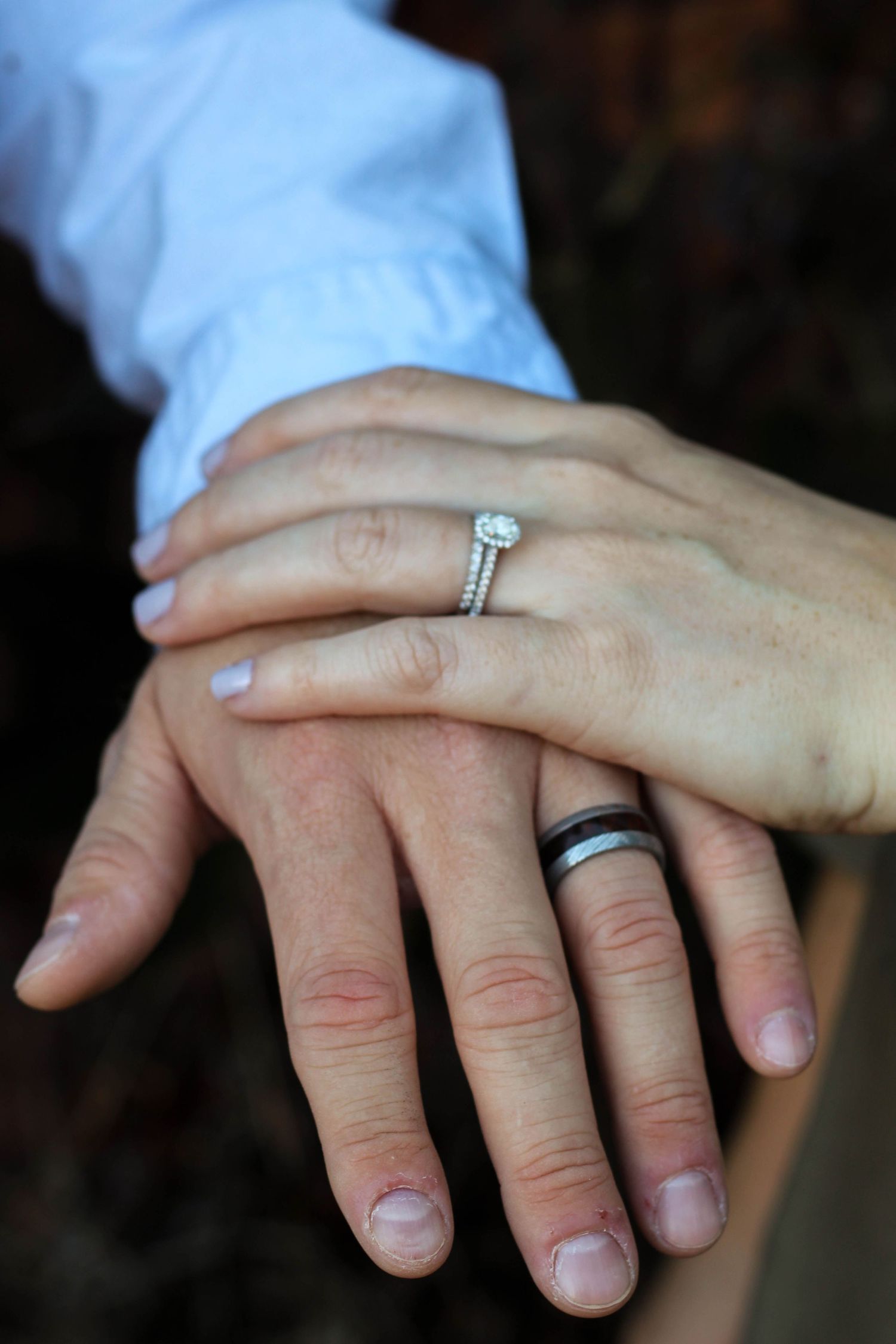 Close-up of hands showing engagement ring and wedding band.