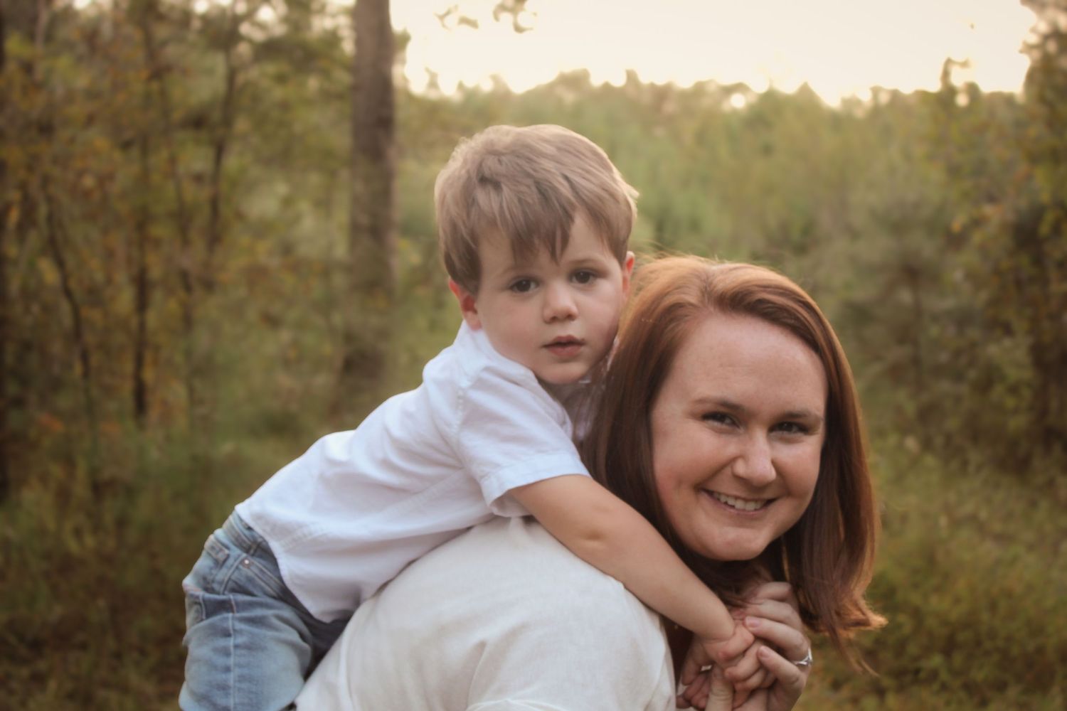 Candid family photo session in a golden autumn forest setting with playful interactions.