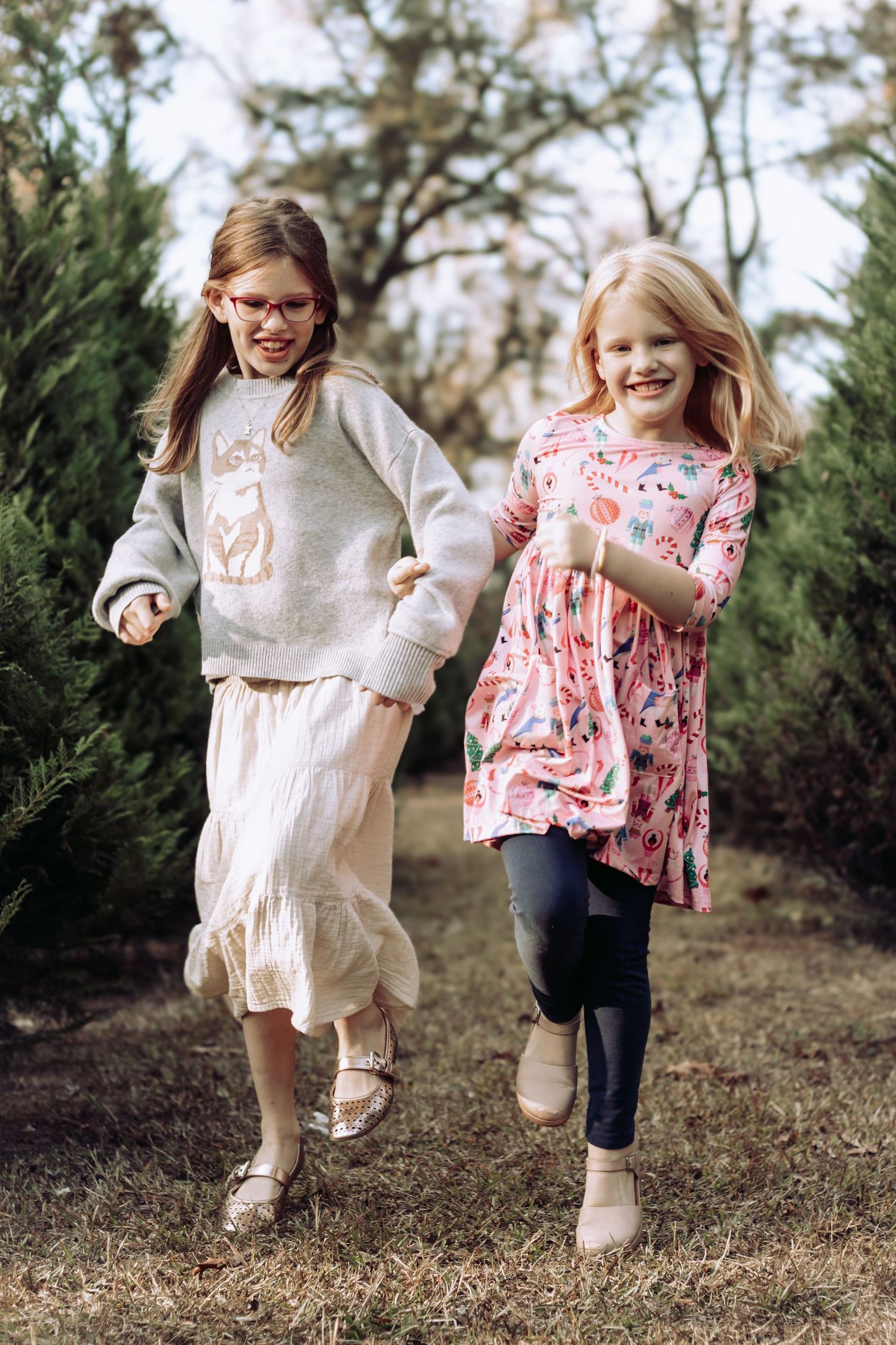 Two children running and playing together outdoors in matching outfits during golden hour.