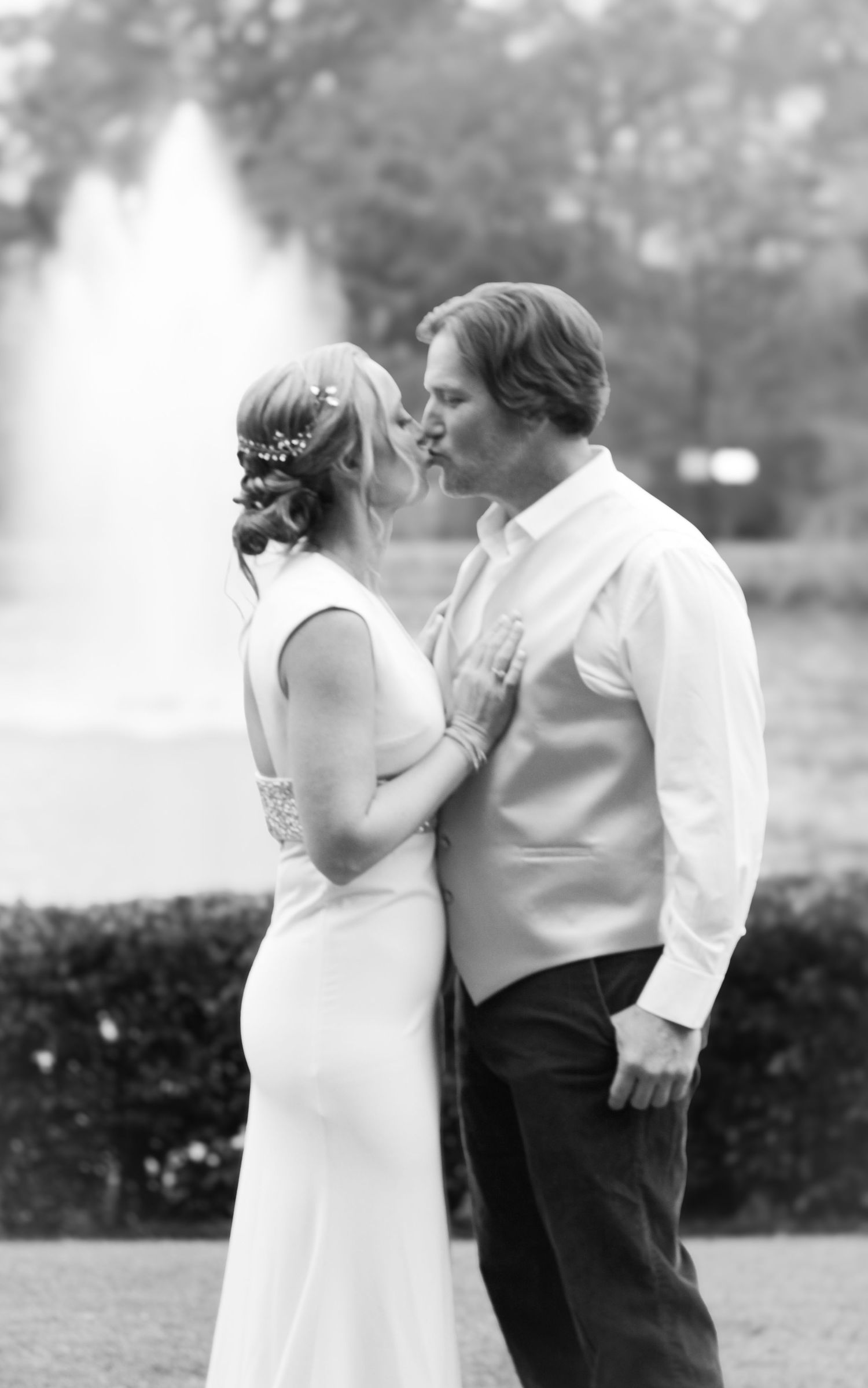 A couple shares an intimate black and white moment in formal wedding attire.