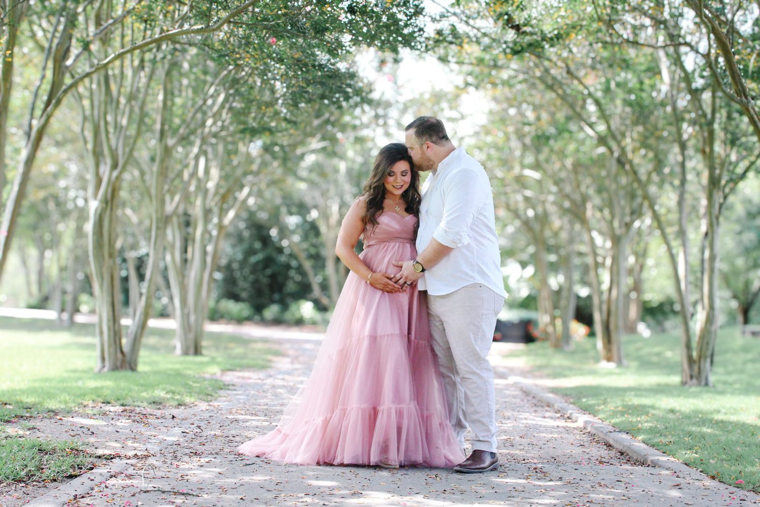 A series of tender maternity photos captured on a tree-lined path in natural lighting.