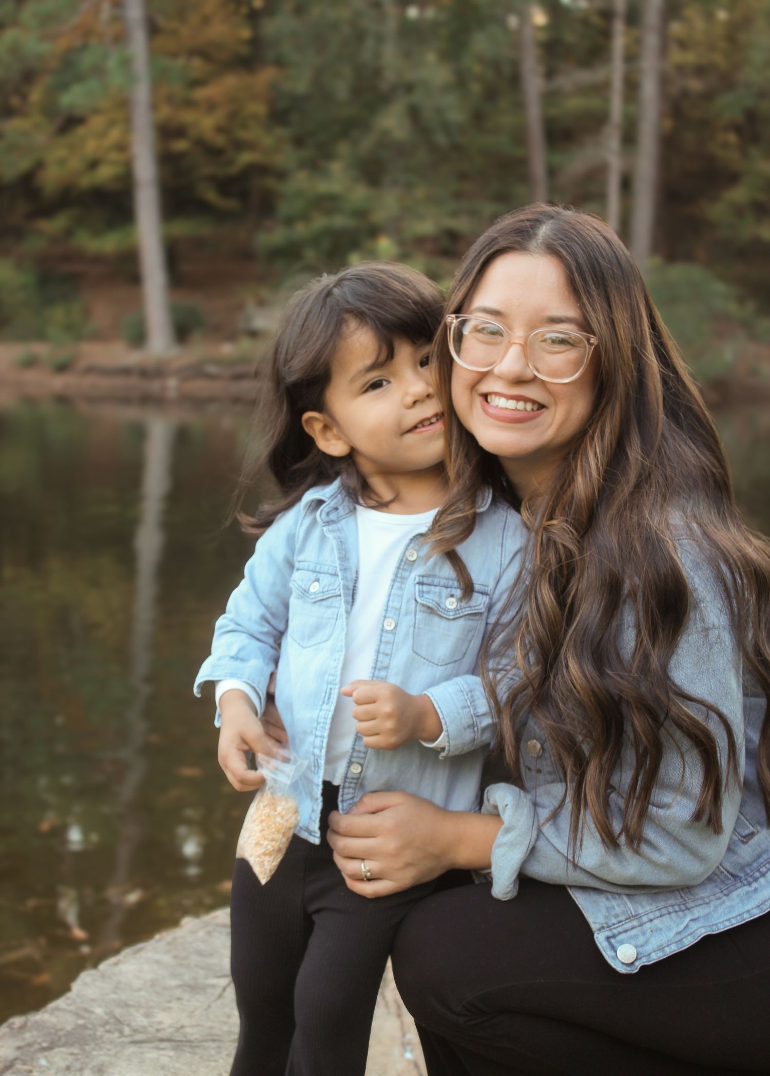 Heartwarming lakeside photoshoot featuring matching denim outfits and natural laughter.