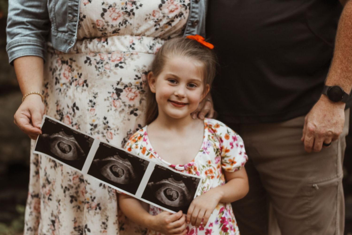 Family maternity photo session showing ultrasound pictures in autumn setting.