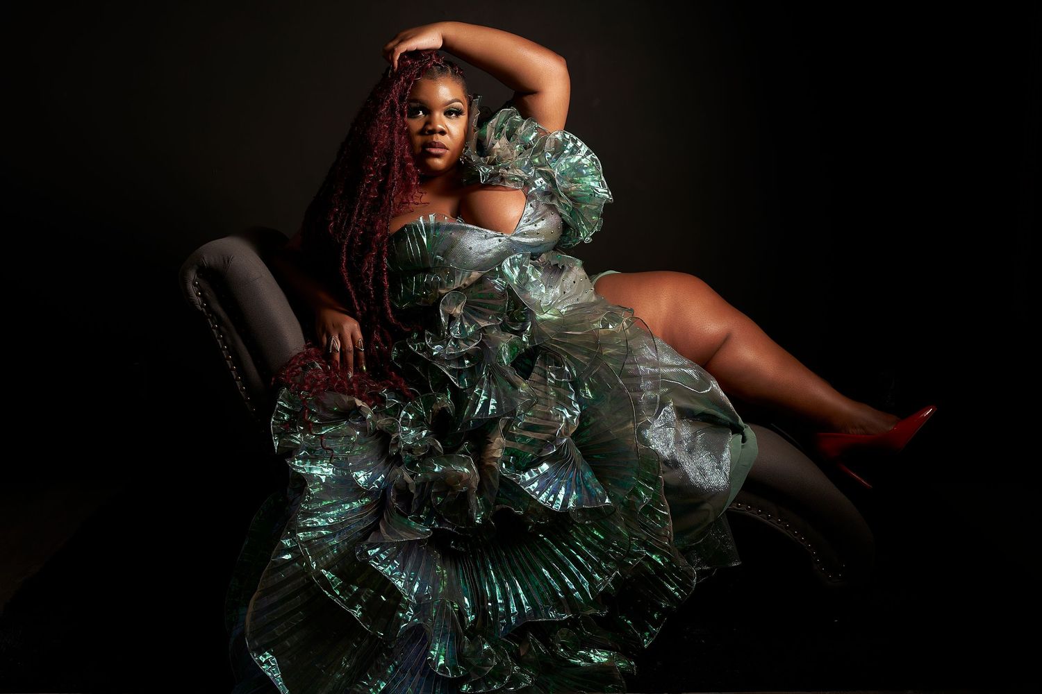 A dramatic fashion portrait featuring a mint green ruffled gown against a dark background.