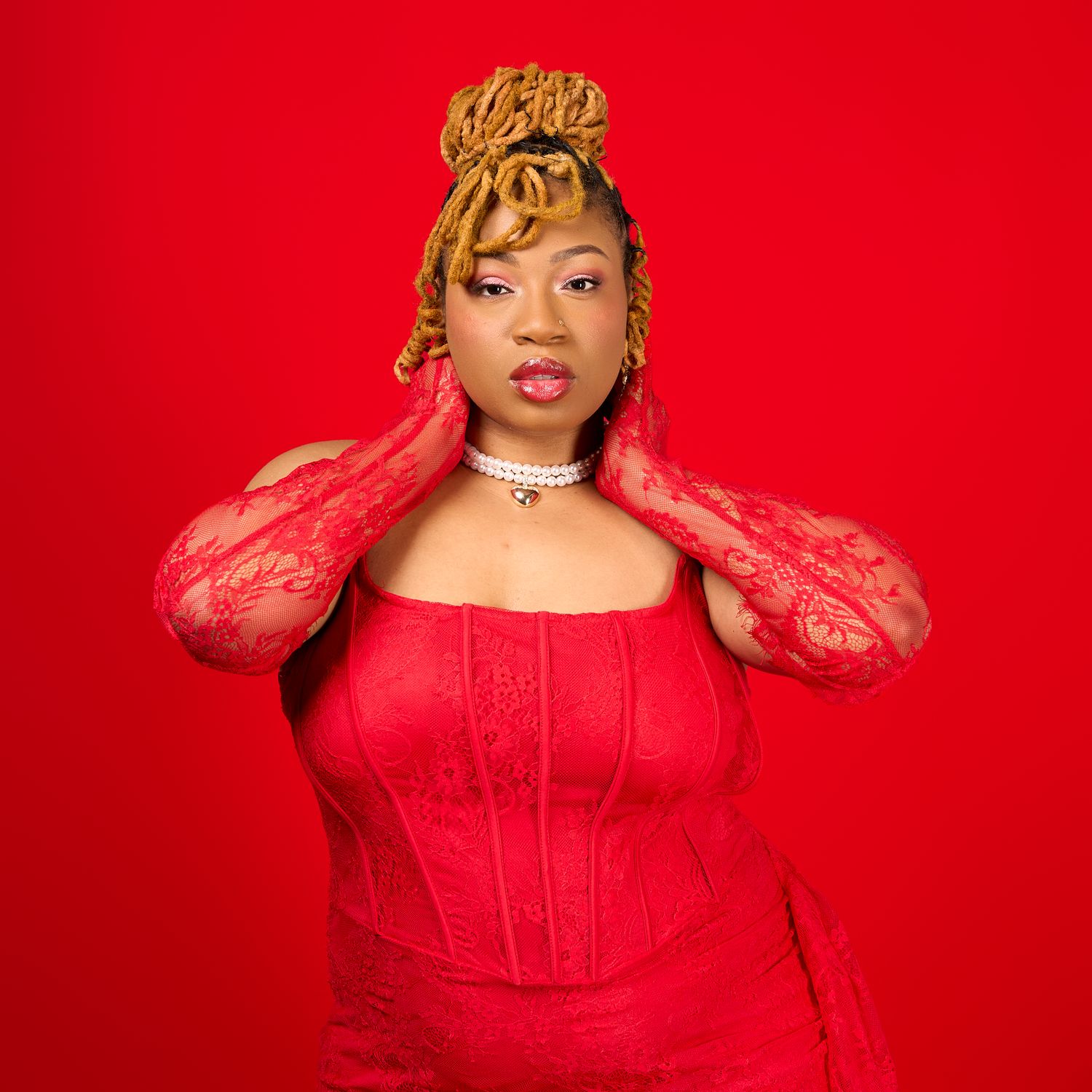 A woman in a vibrant red outfit poses against a matching red background creating a monochromatic fashion portrait.