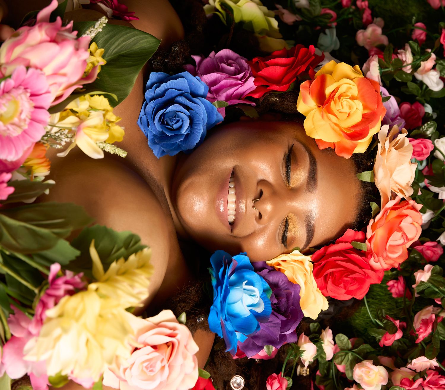 Artistic beauty portrait surrounded by colorful roses and flowers in vibrant hues.
