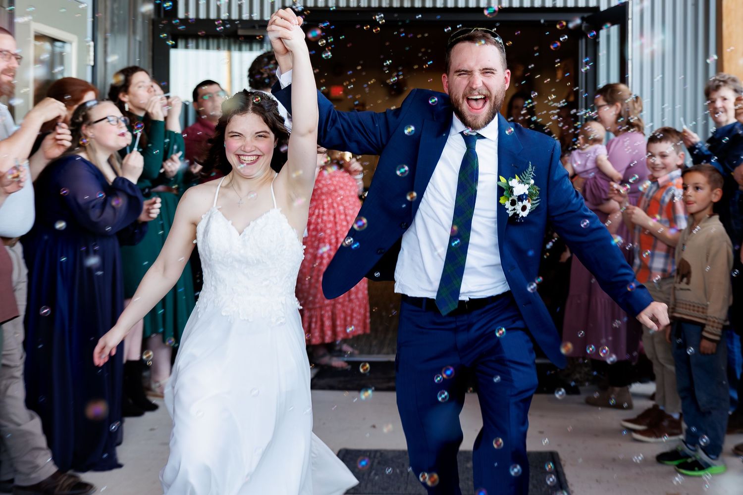 Wedding party celebrates with joyful dance moves in a reception line as guests cheer and clap along.